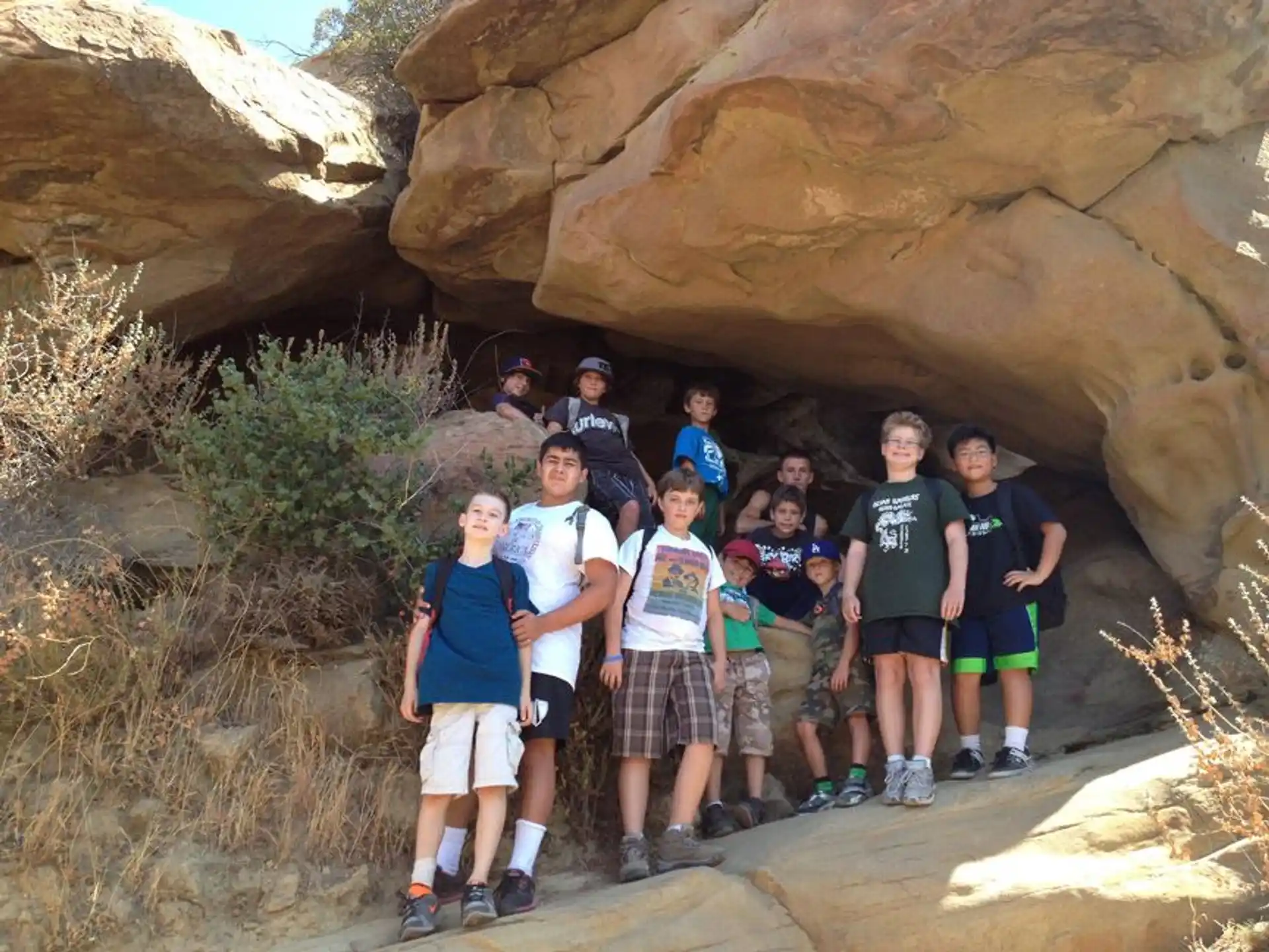 a group of people posing for a photo in front of a rock formation