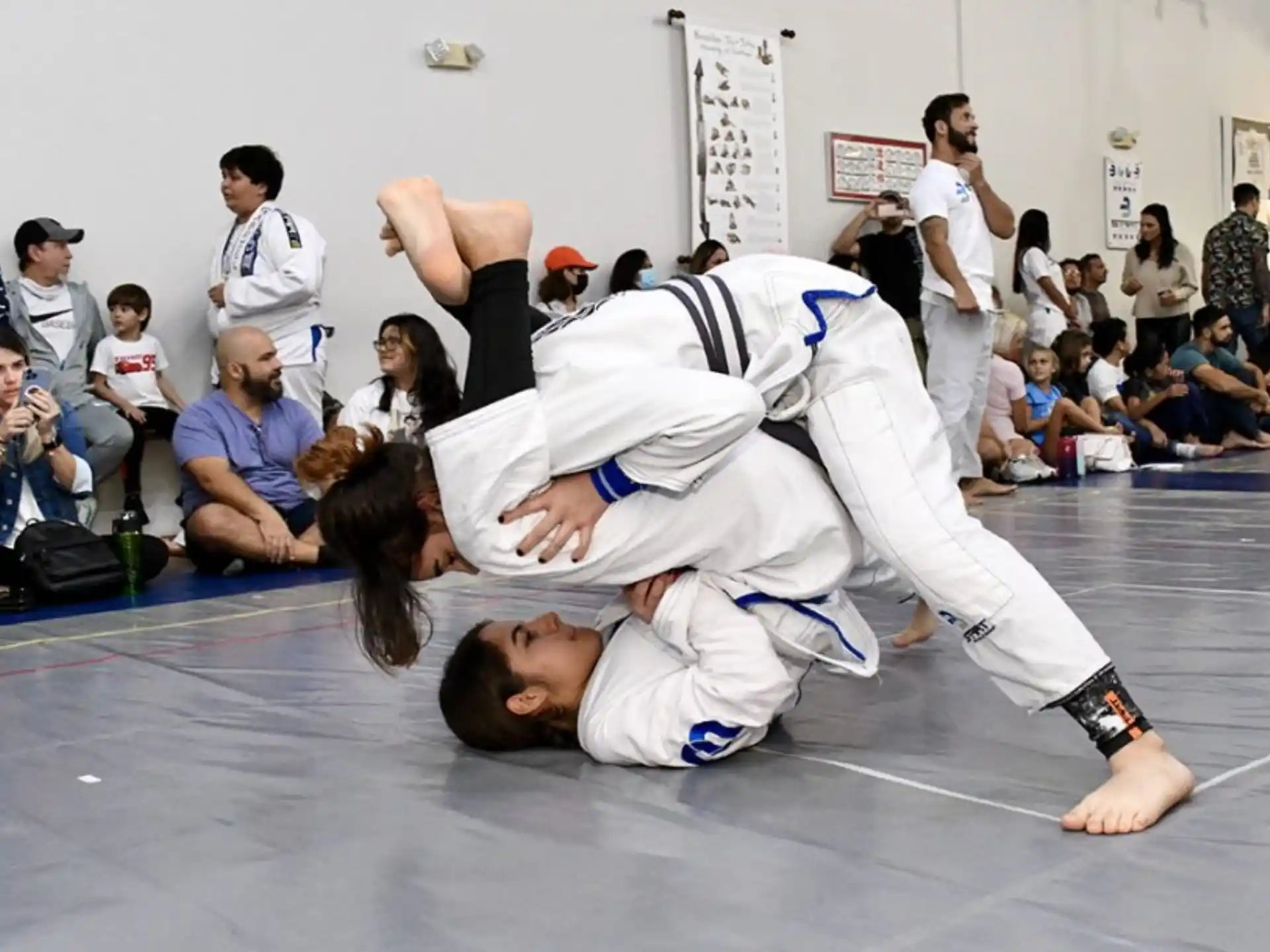 a person kicking another man in the face in front of a crowd