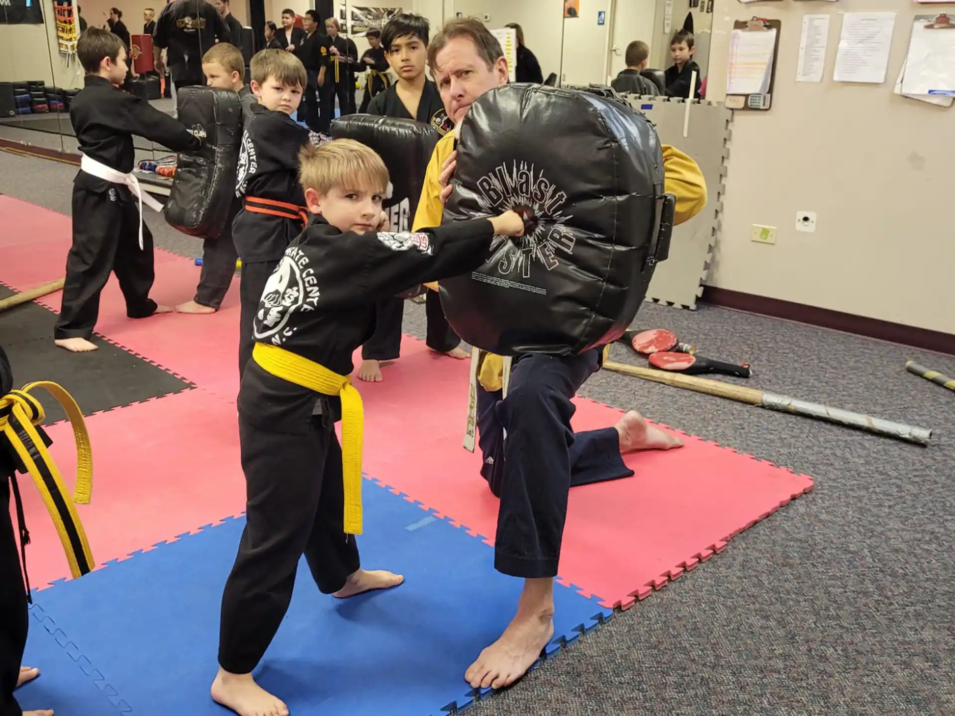 a person and a boy in a karate uniform in a room with other people