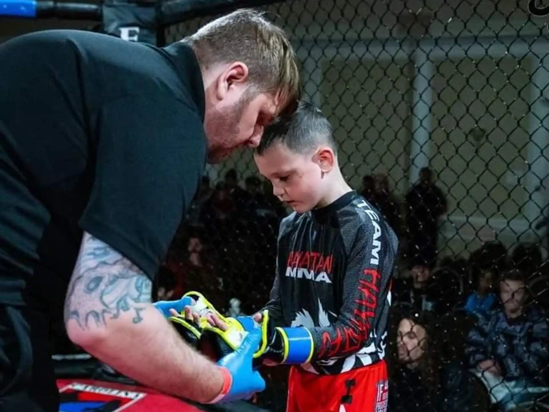 a man in a black shirt and red gloves with a boy in a red shirt with a crowd