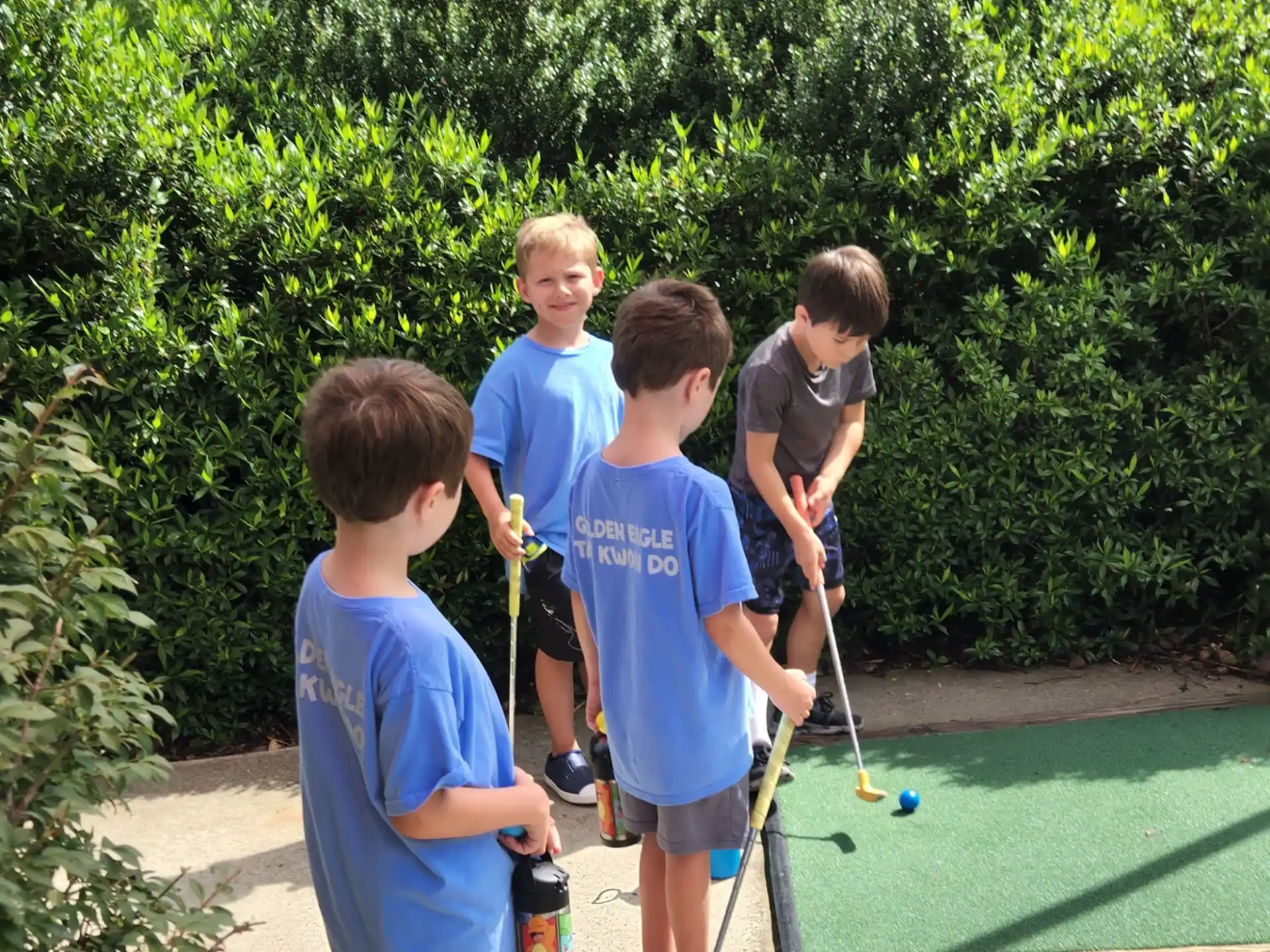 a group of boys playing mini golf