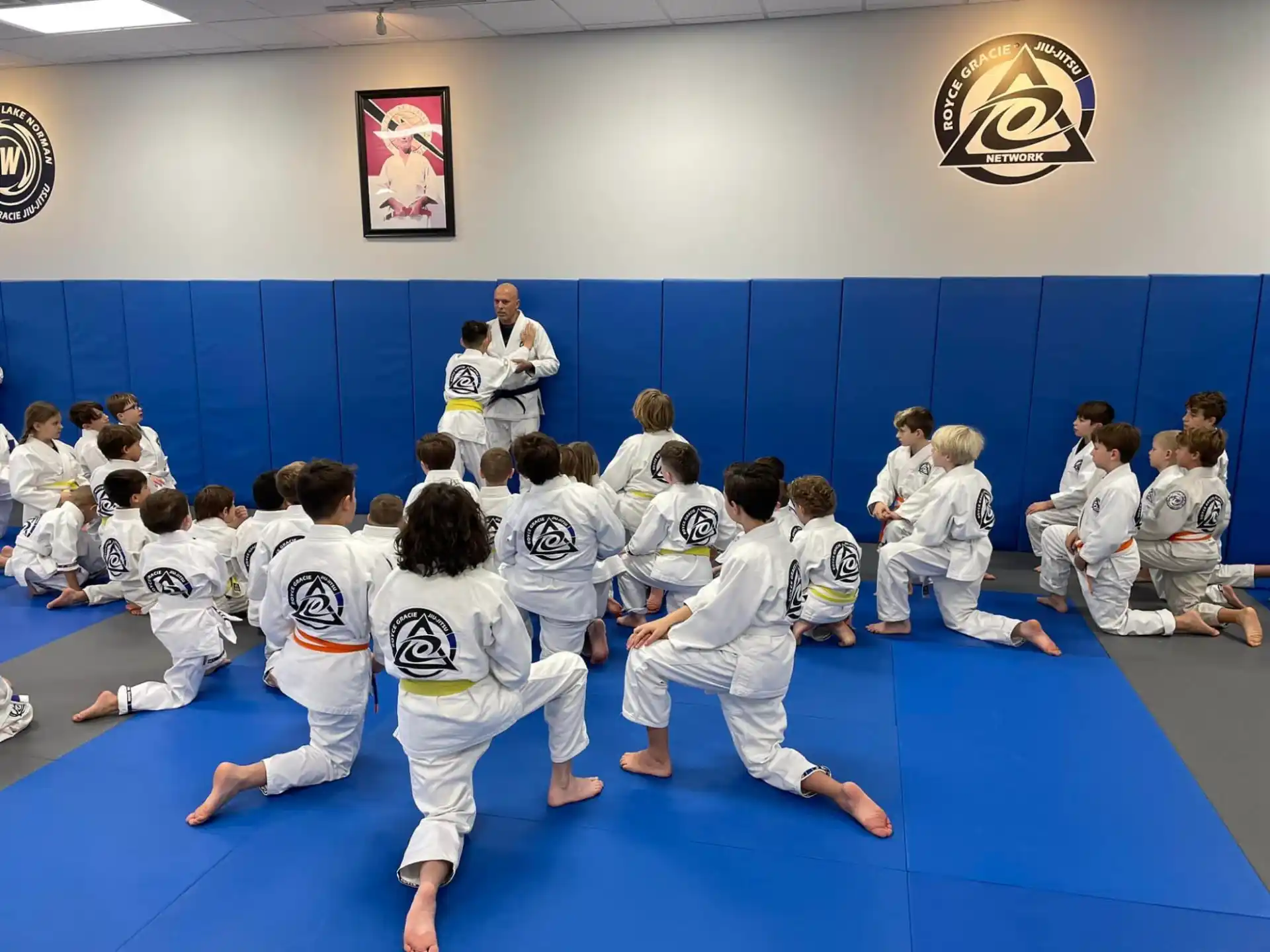 a group of people in white uniforms in a room with a person in a white shirt and a