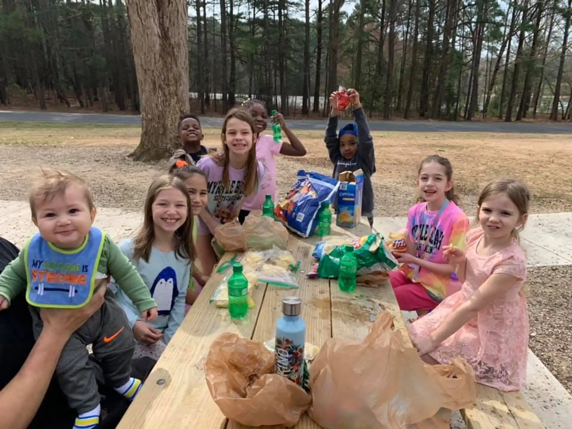a group of children sitting around a table outside