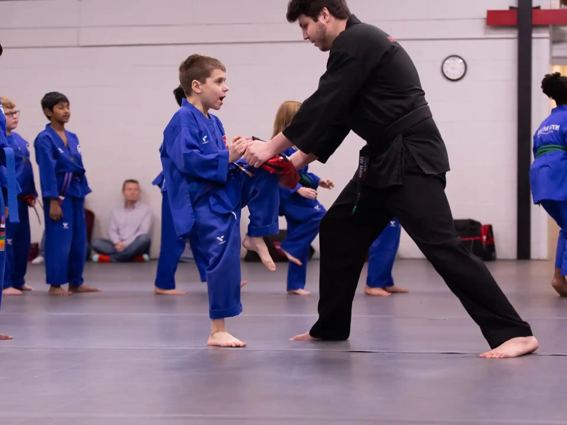 a person and a group of children in karate uniforms