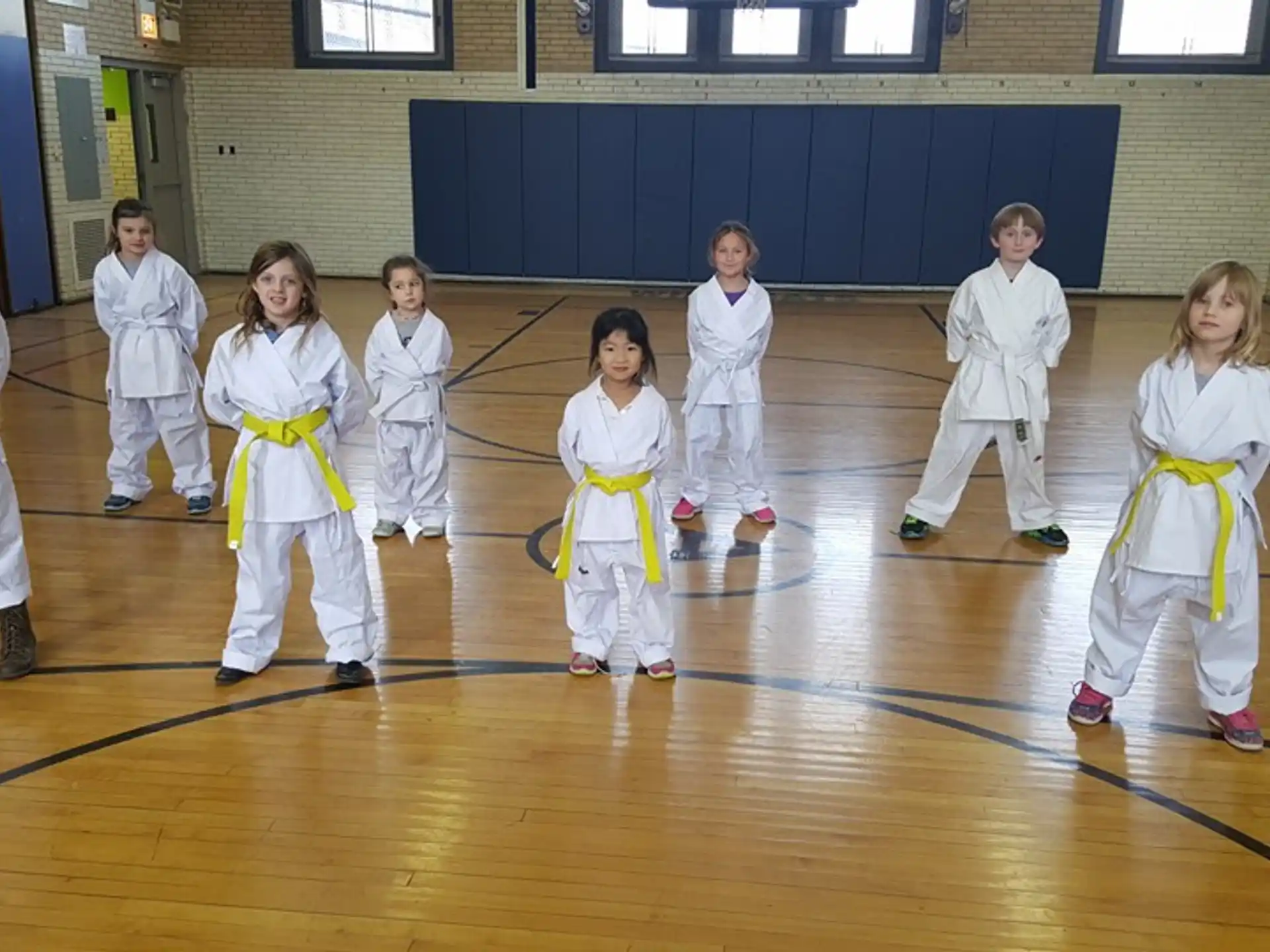 a group of children in white karate uniforms on a wooden floor