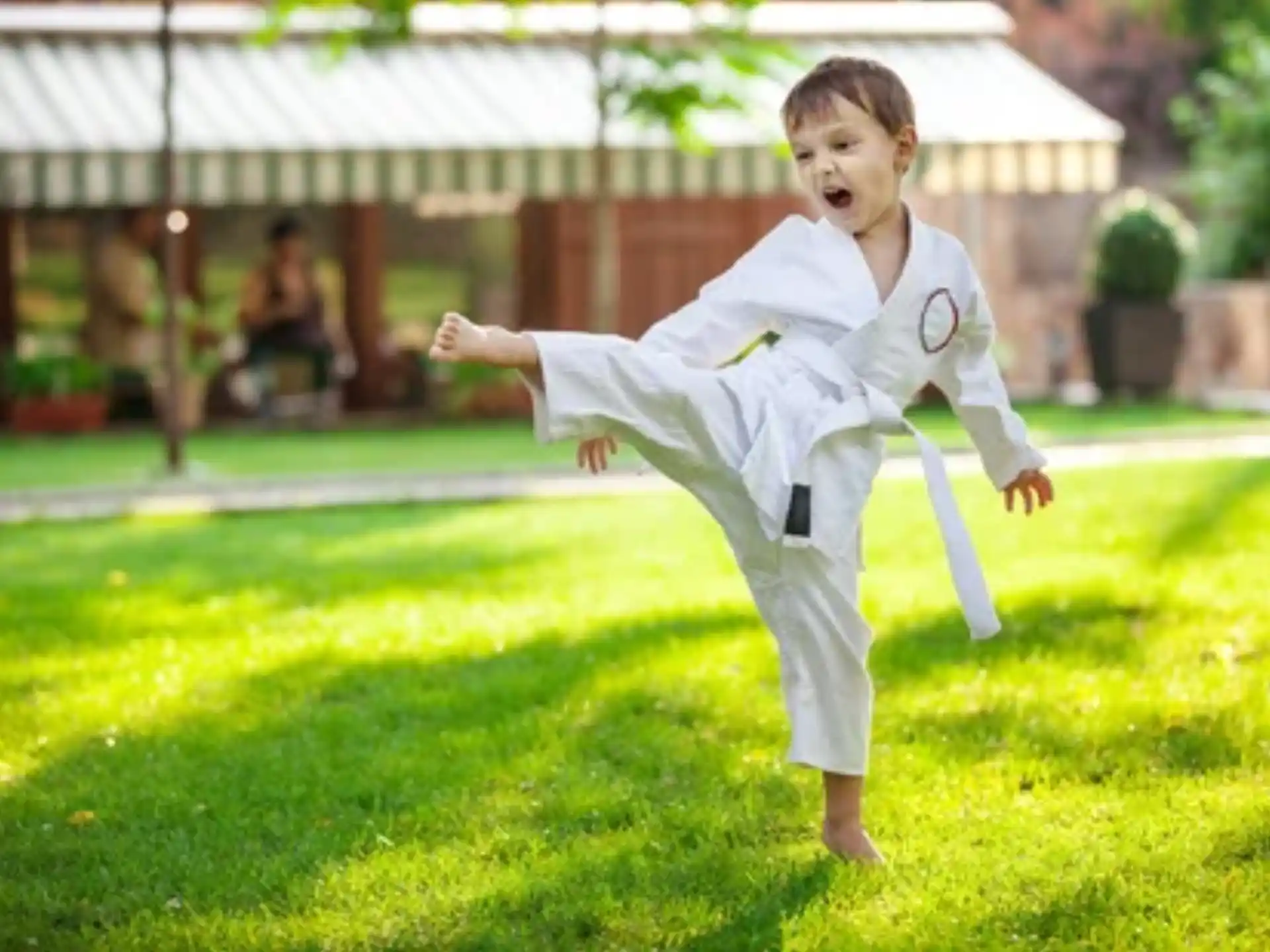 a boy in a karate uniform jumping in the air
