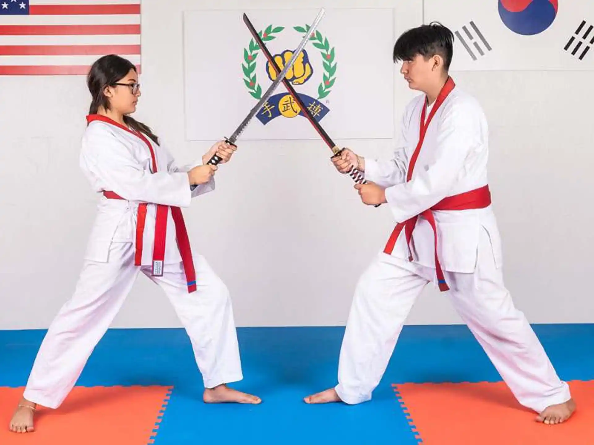 a man and a woman in karate uniforms holding a sword