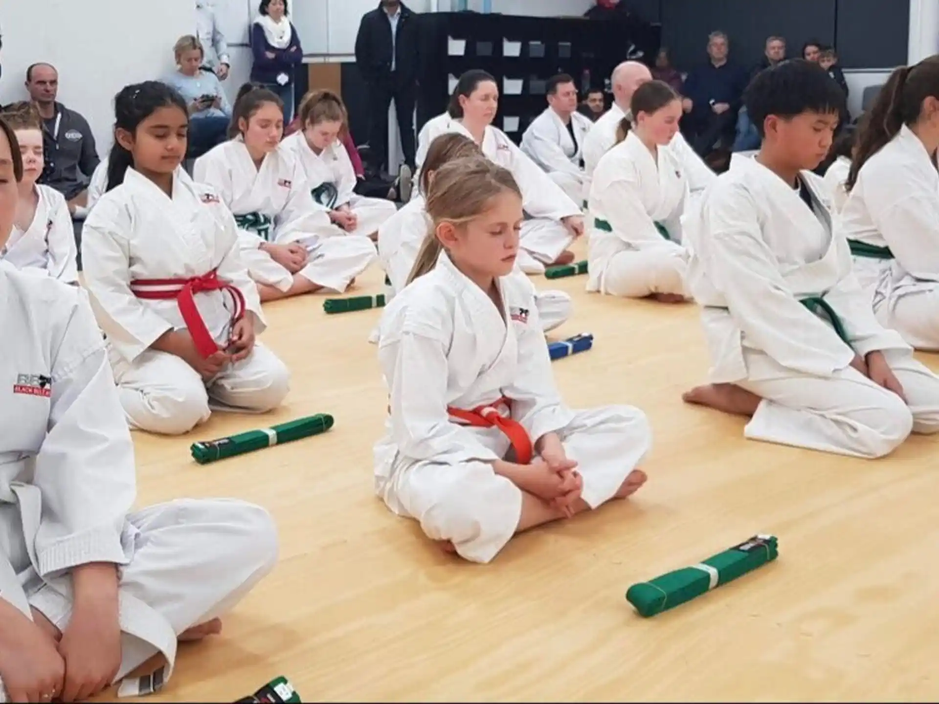 a group of people in white karate uniforms sitting on the floor