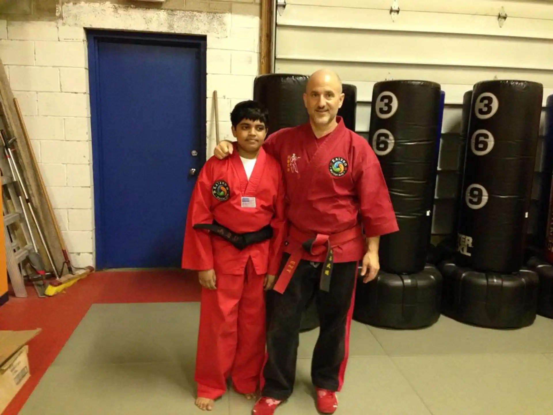a person and a boy in red uniforms standing in front of a stack of tires