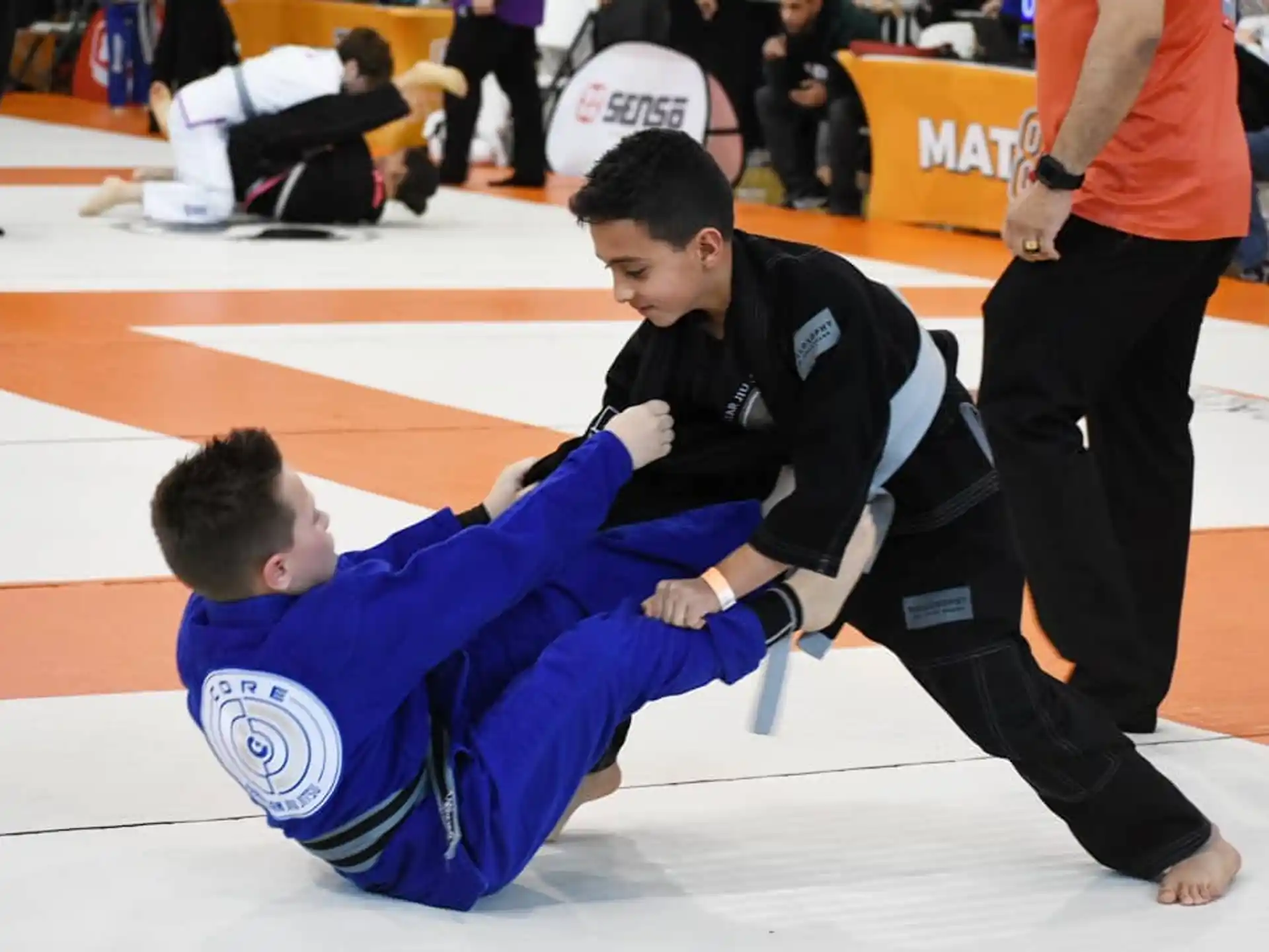 a man in a blue shirt doing a push up on another man in a black and white uniform