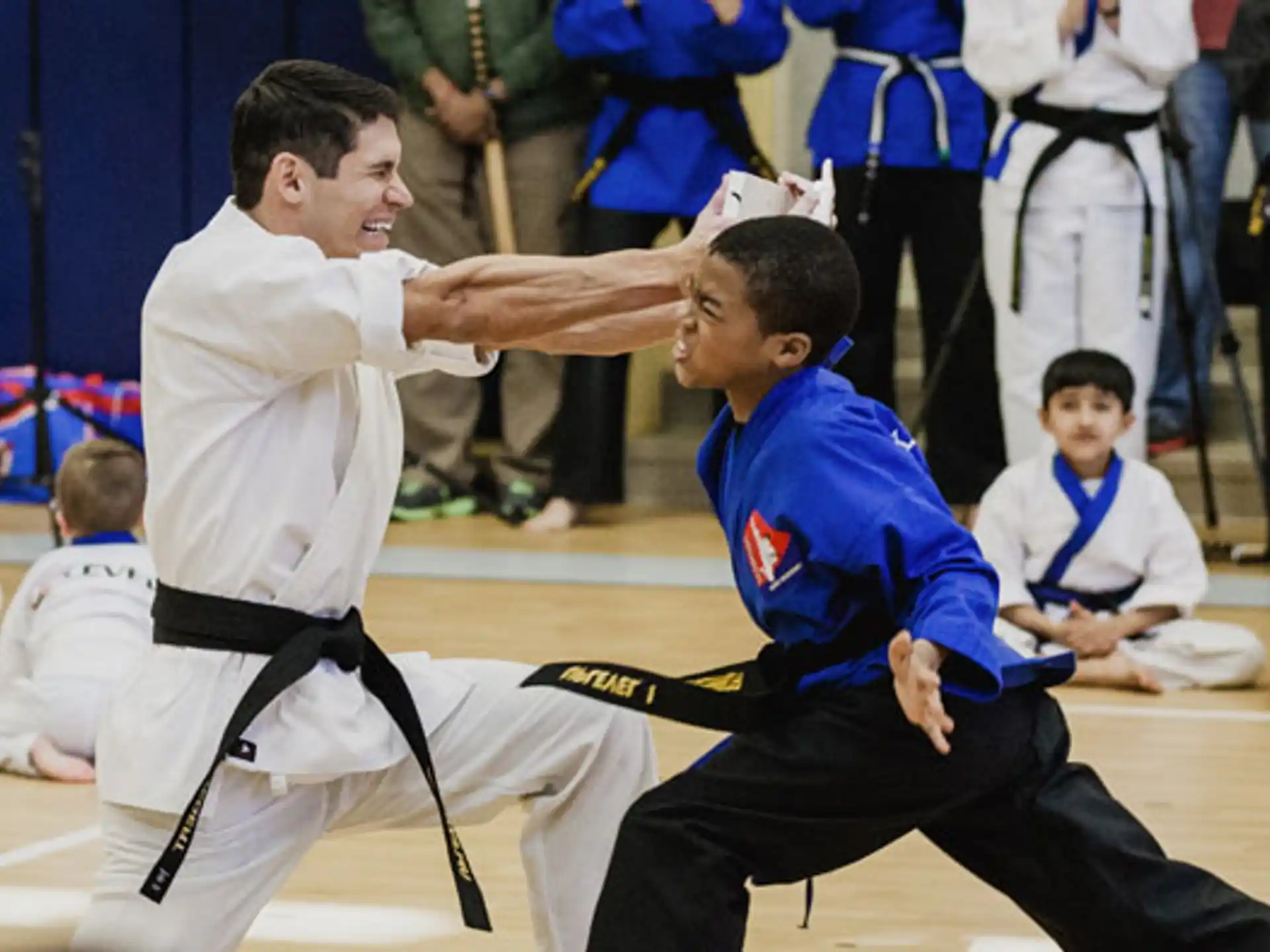 a person in a karate uniform kicking another man in the face