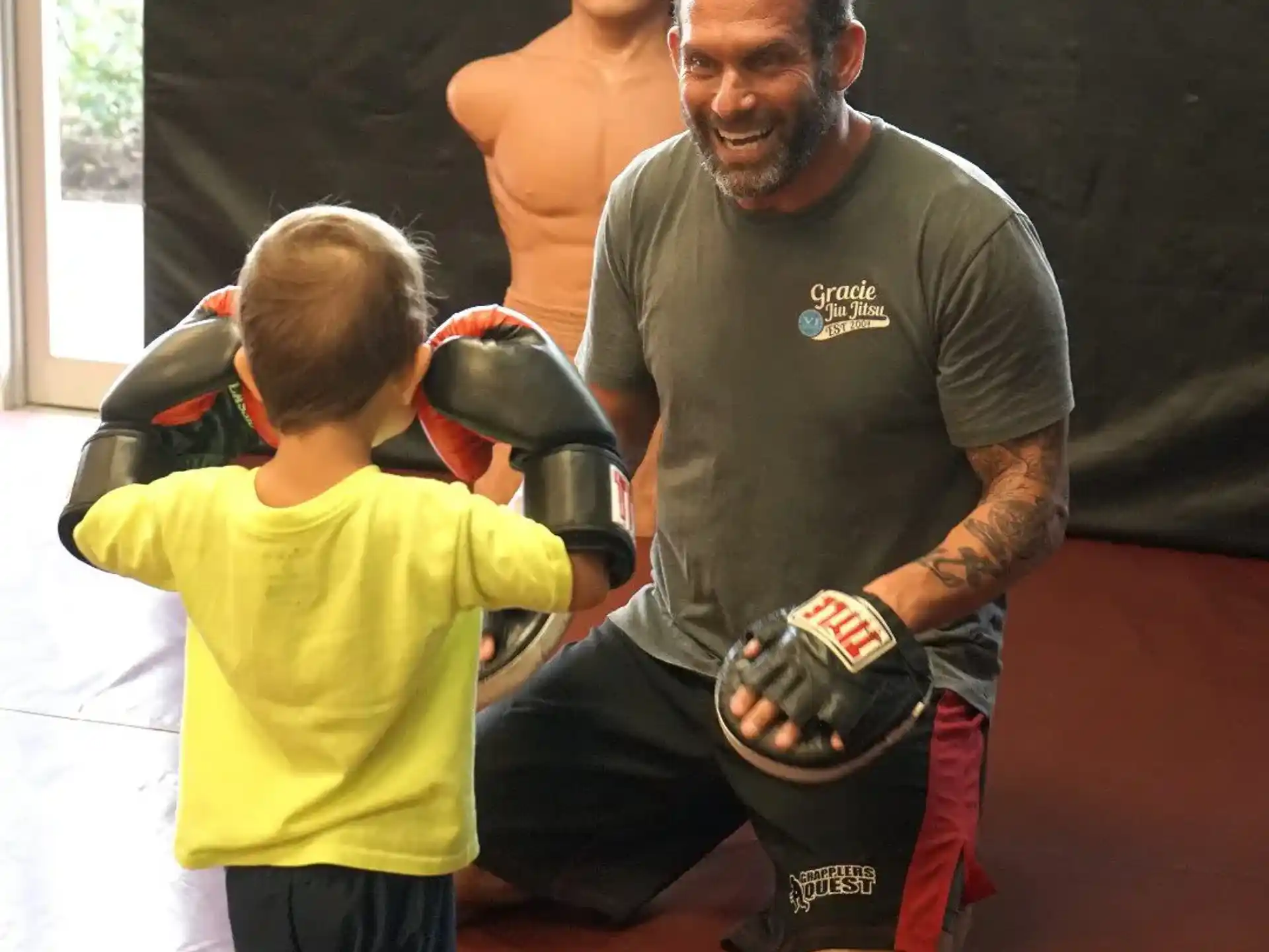 a man in a boxing ring with a boy in a yellow shirt