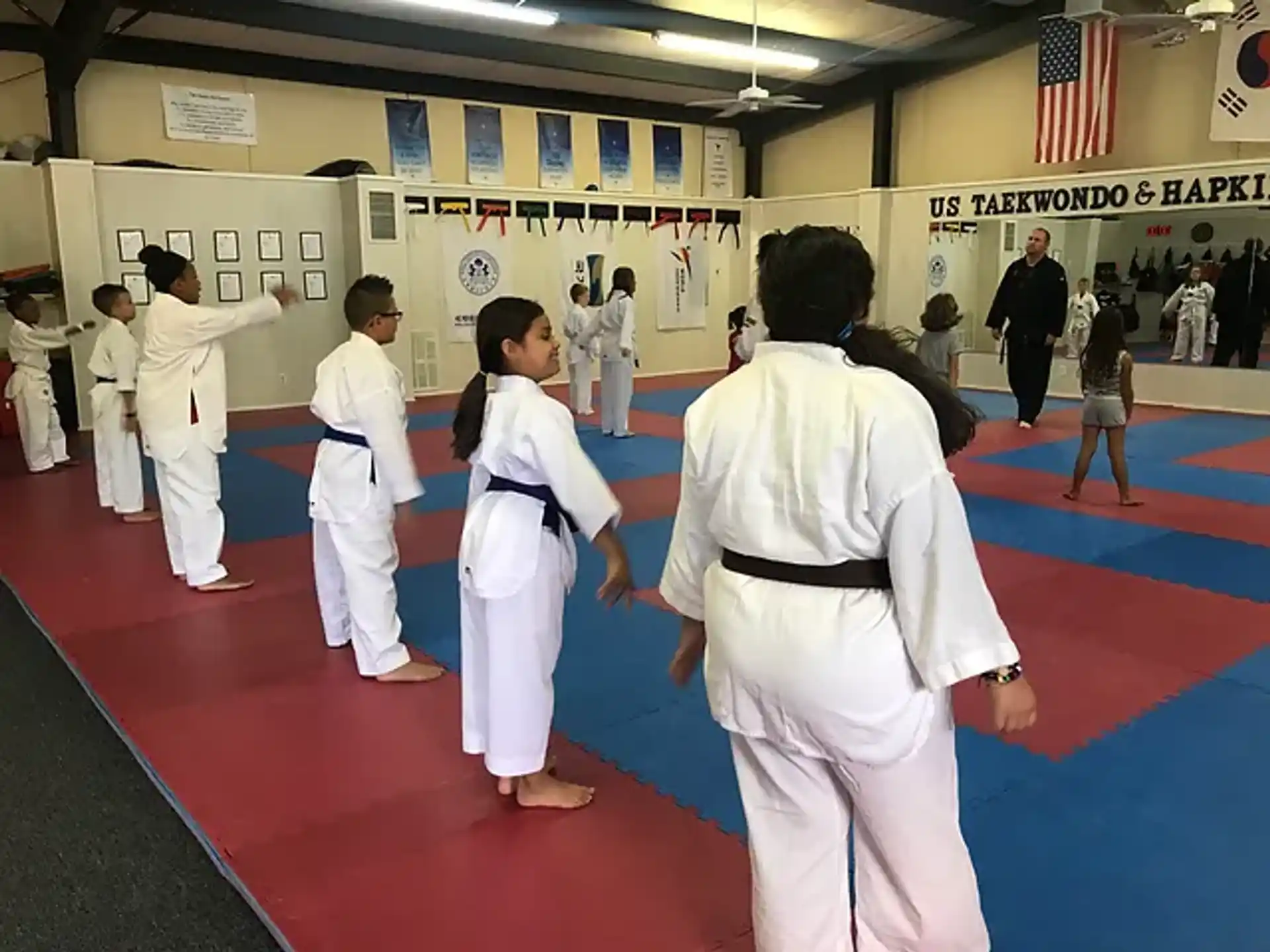 a group of people in white karate uniforms in a room with flags