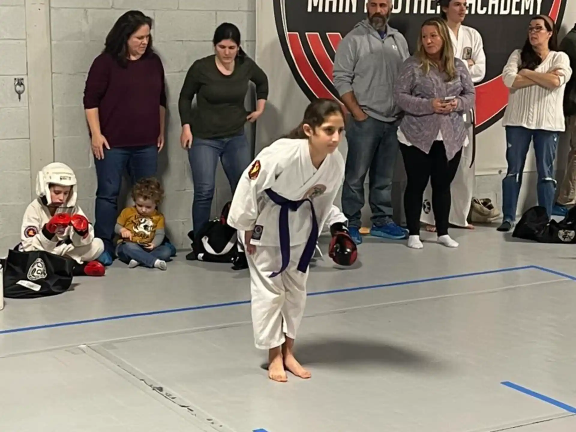 a group of people watching a boy do karate