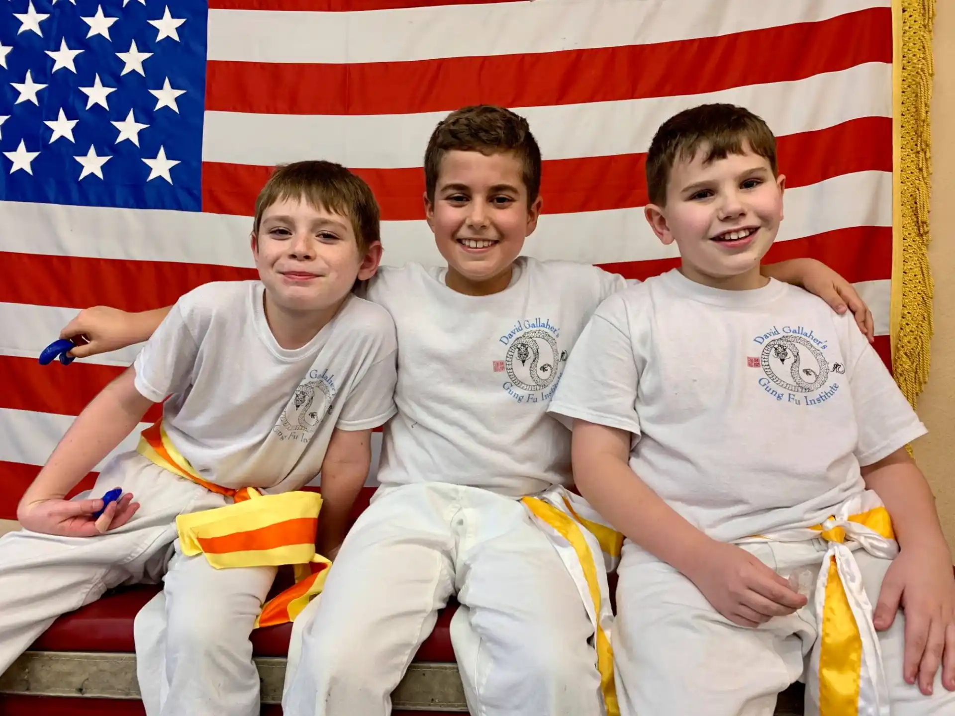 a group of boys sitting on a bench in front of a flag