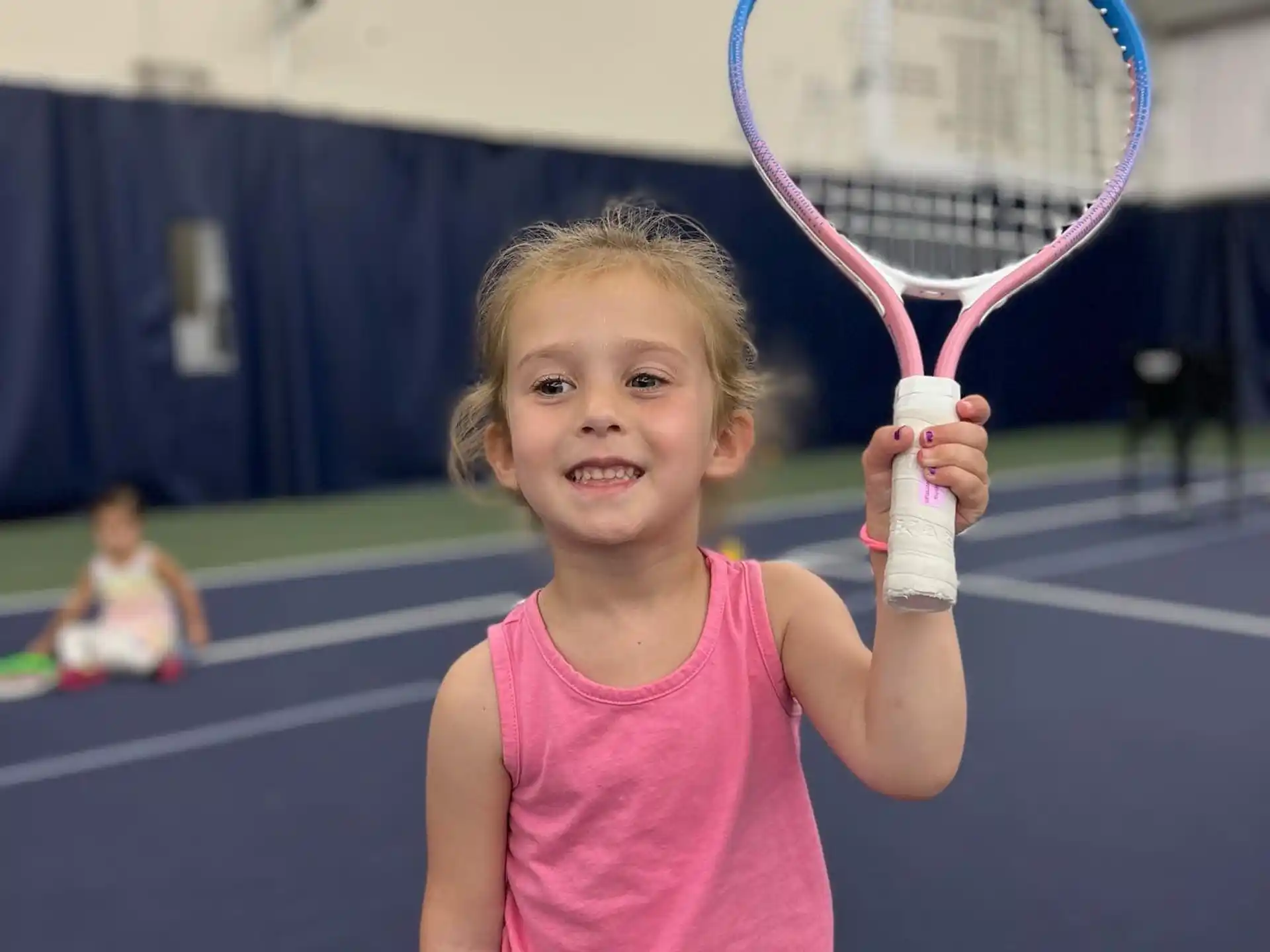 a little girl holding a tennis racket