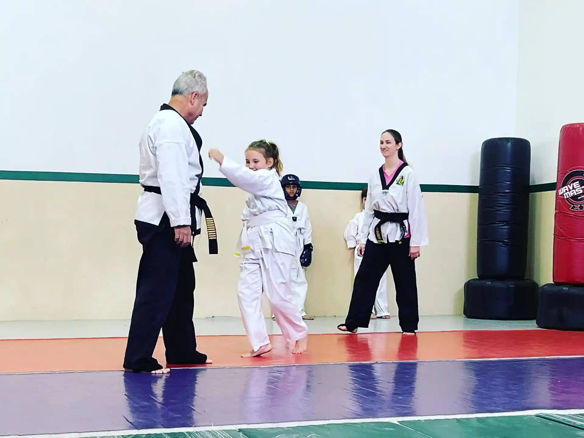 a man and a woman with children in karate uniforms