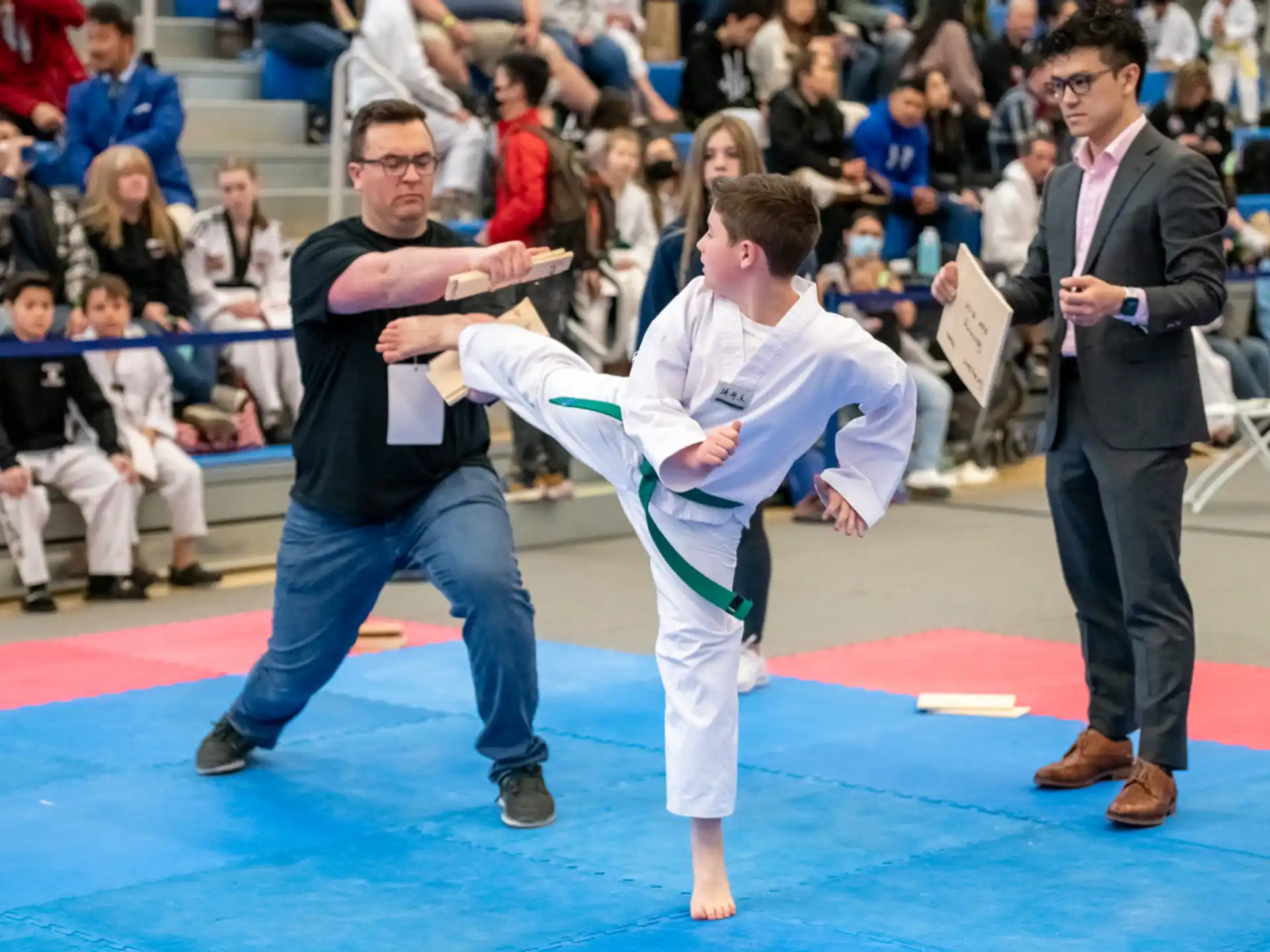 a person kicking another man in the face with a crowd watching
