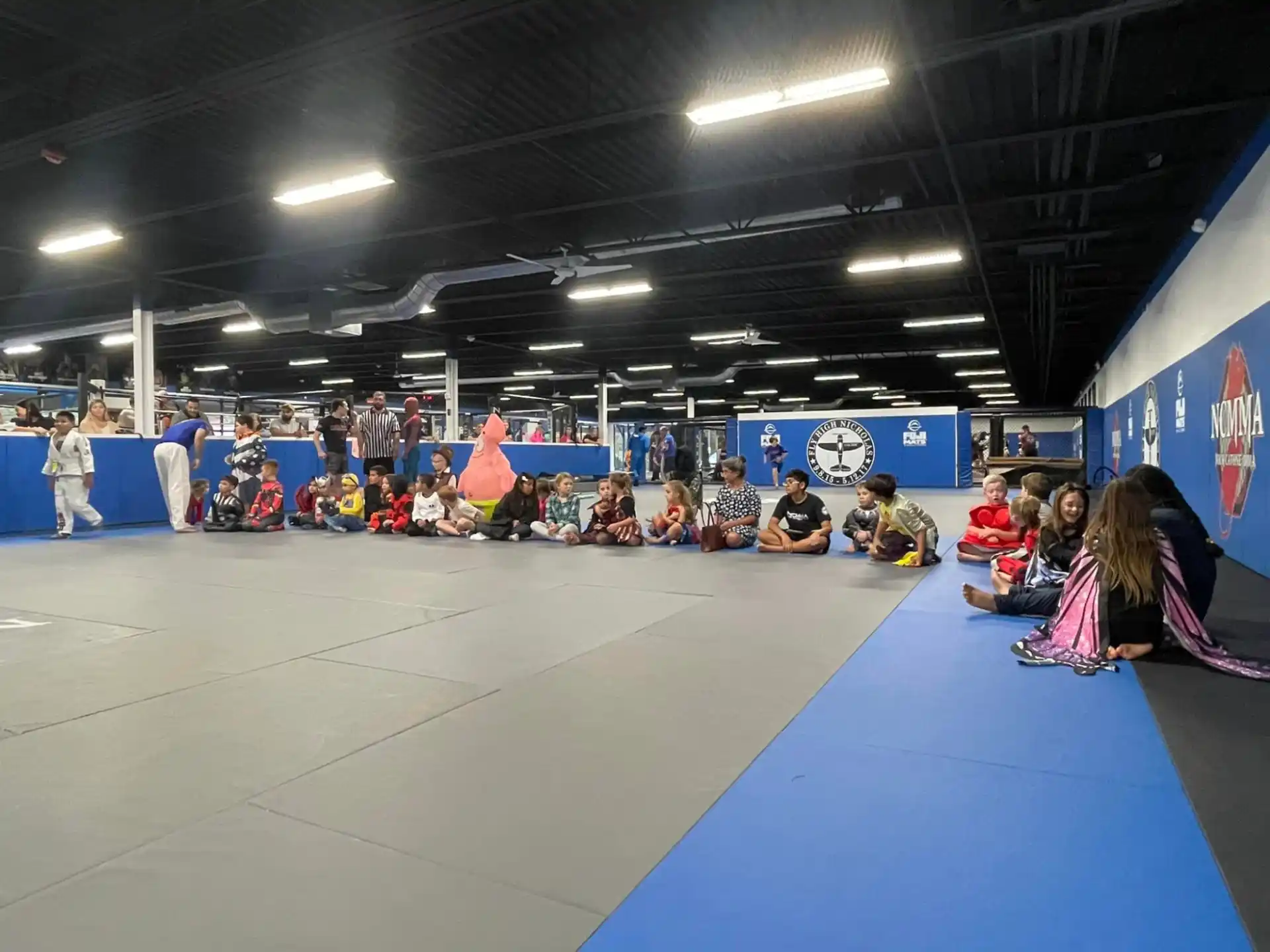 a group of people sitting on a blue mat in a room with a blue floor and a blue