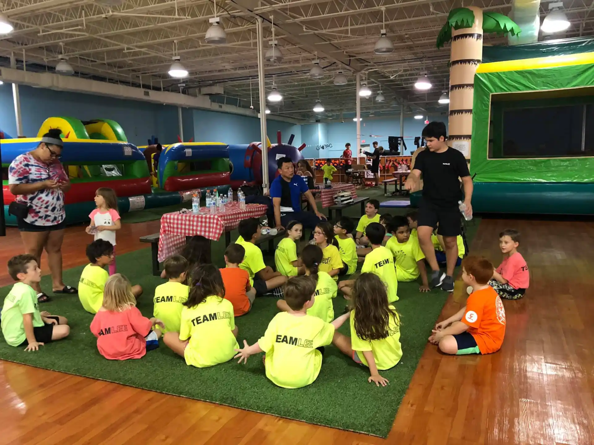 a group of children sitting on the floor in a gym