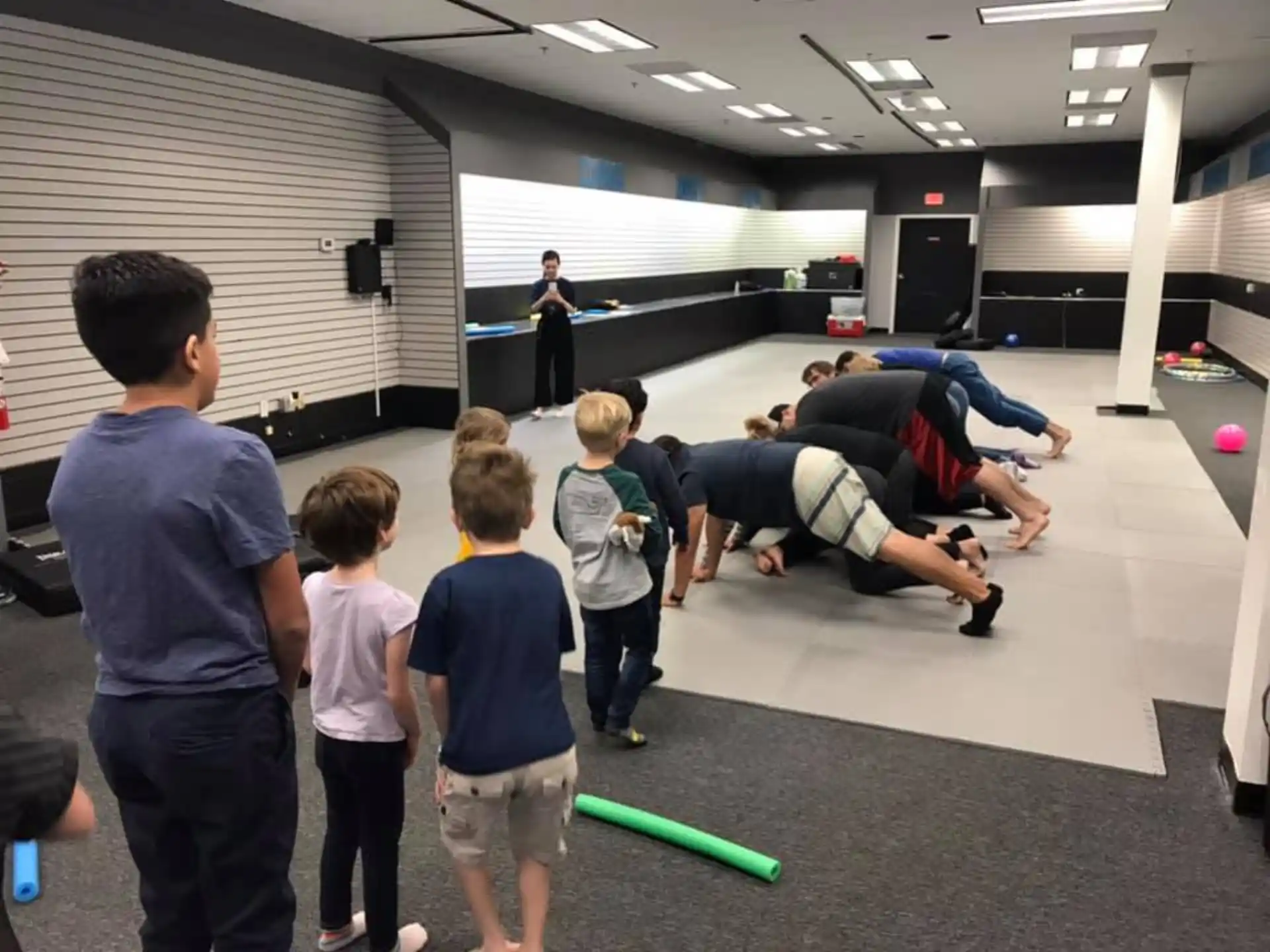 a person doing a push up on a ball with a group of kids