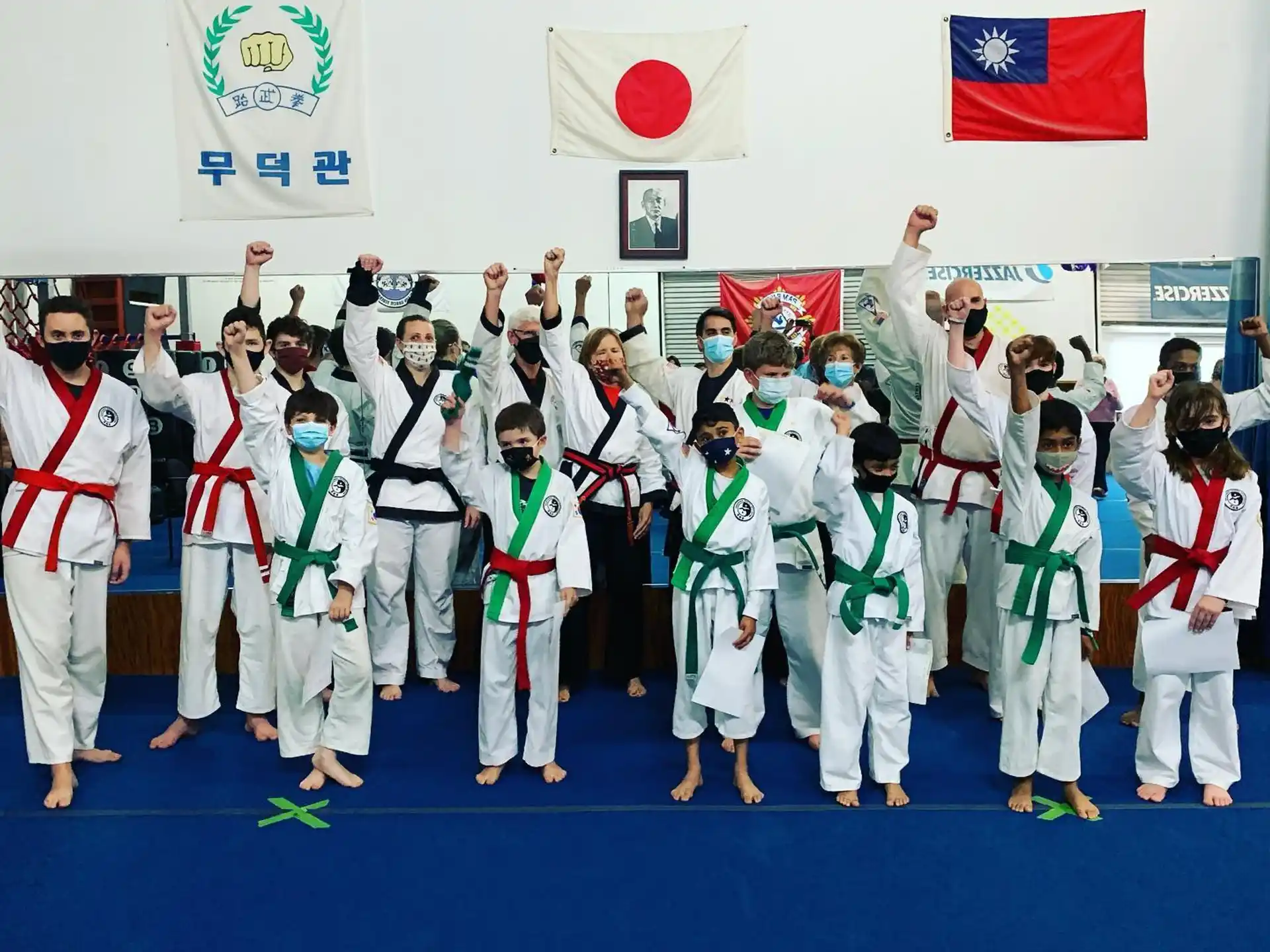 a group of people in white karate uniforms holding up their hands