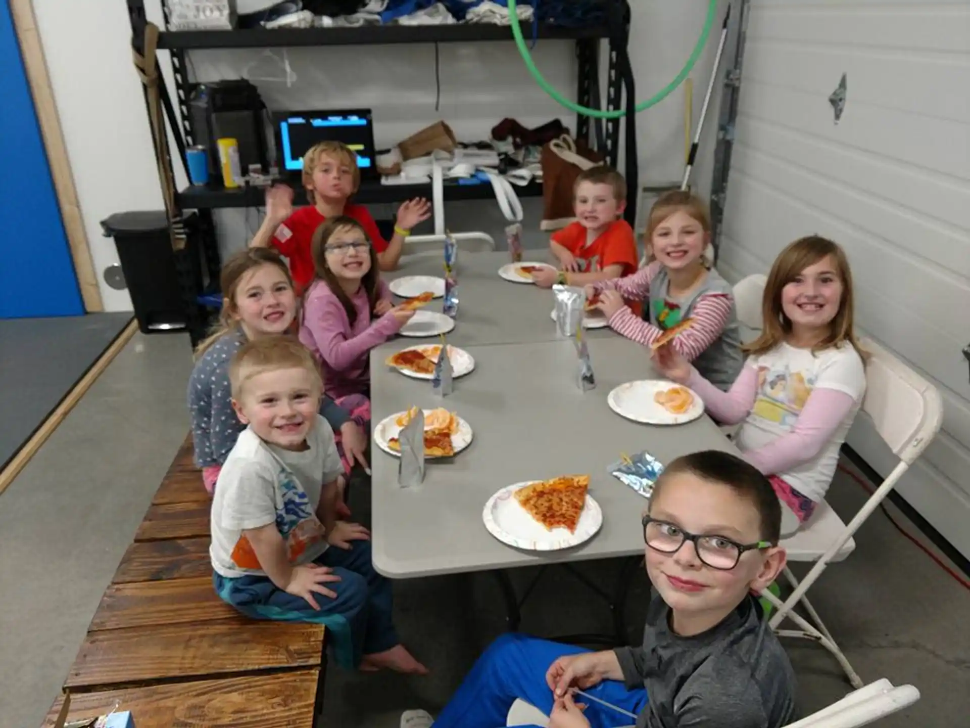 a group of children sitting around a table eating pizza