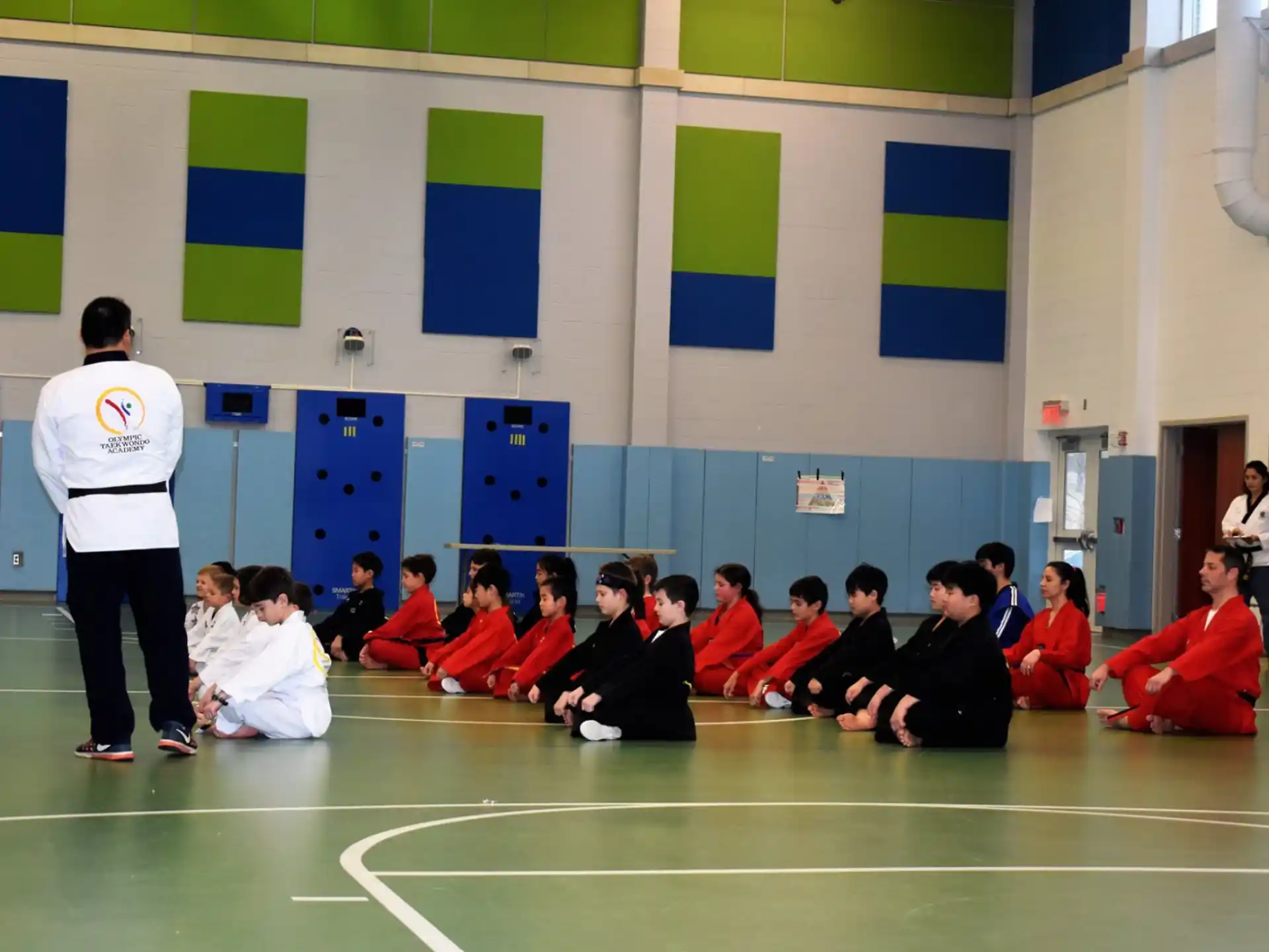 a group of people sitting on the floor in a gym