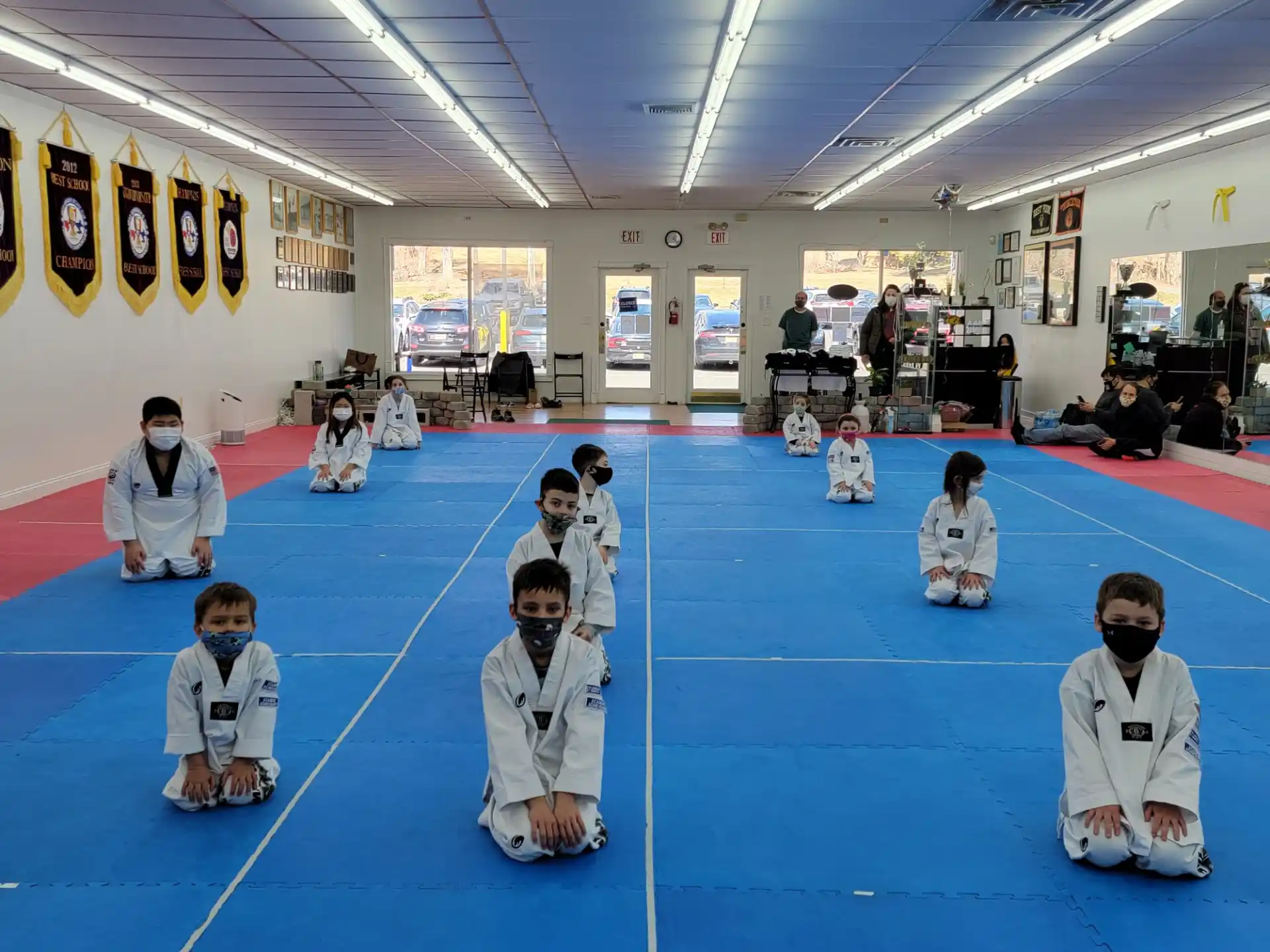 a group of people in white karate uniforms sitting on a blue mat