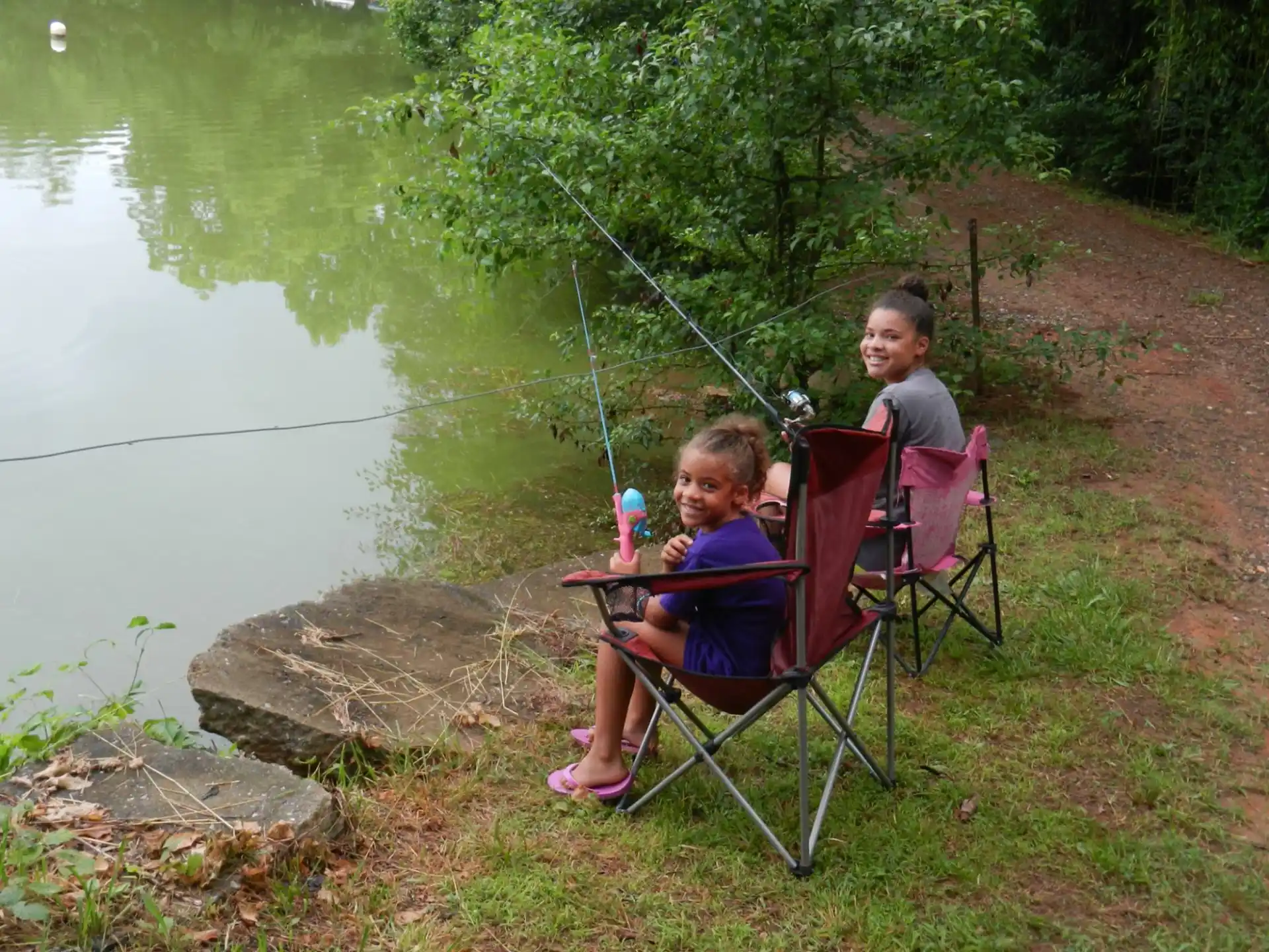 a man and a child sitting in chairs by a lake