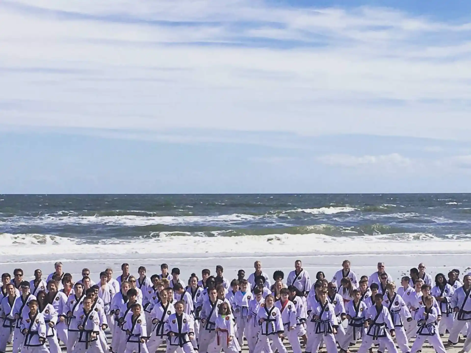 a large group of people in white and black robes on a beach