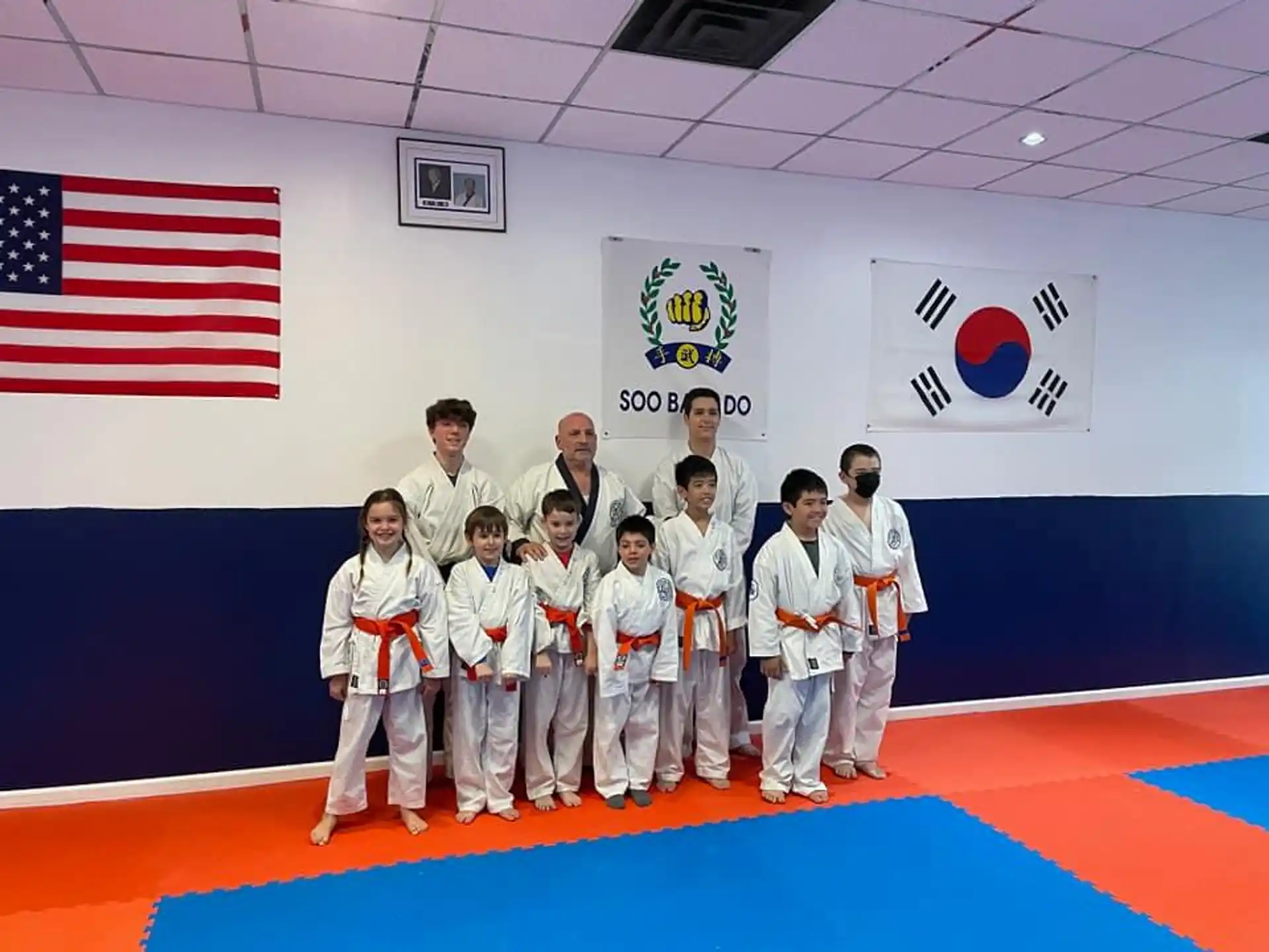 a group of people in white karate uniforms standing on a red mat