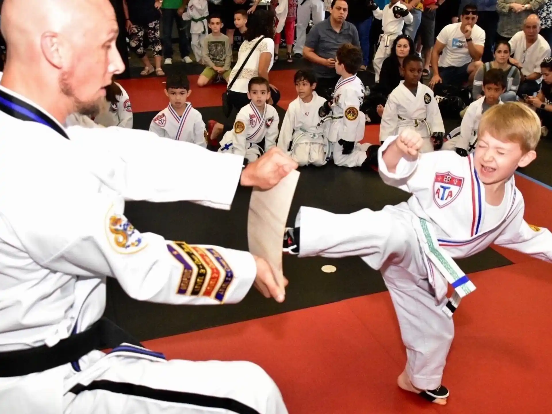 a man and a boy in karate uniforms in front of a crowd