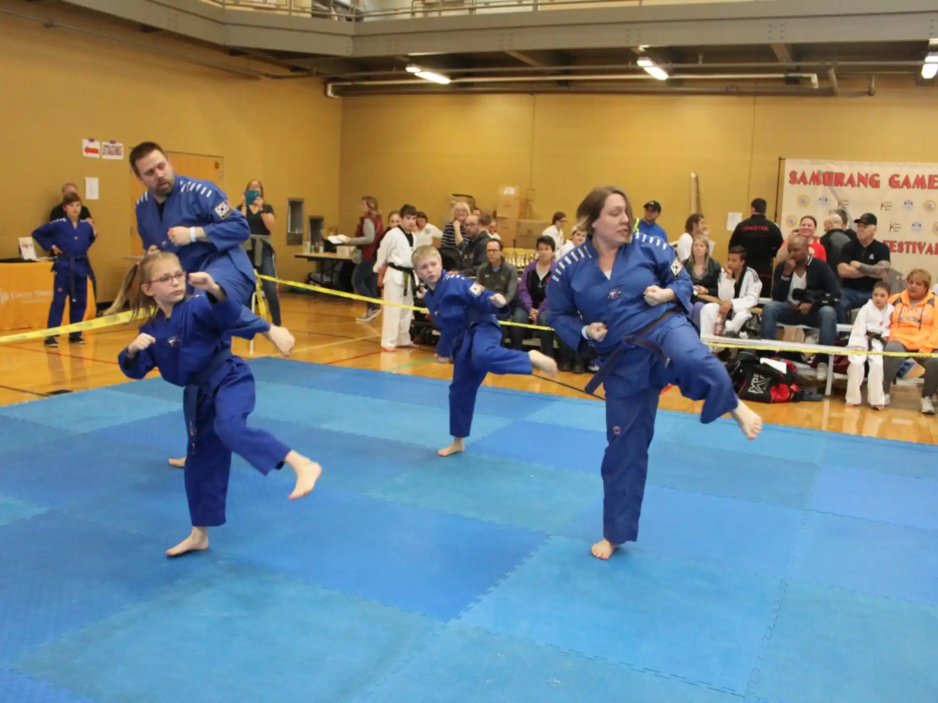 a group of people in blue karate uniforms in a room with a crowd