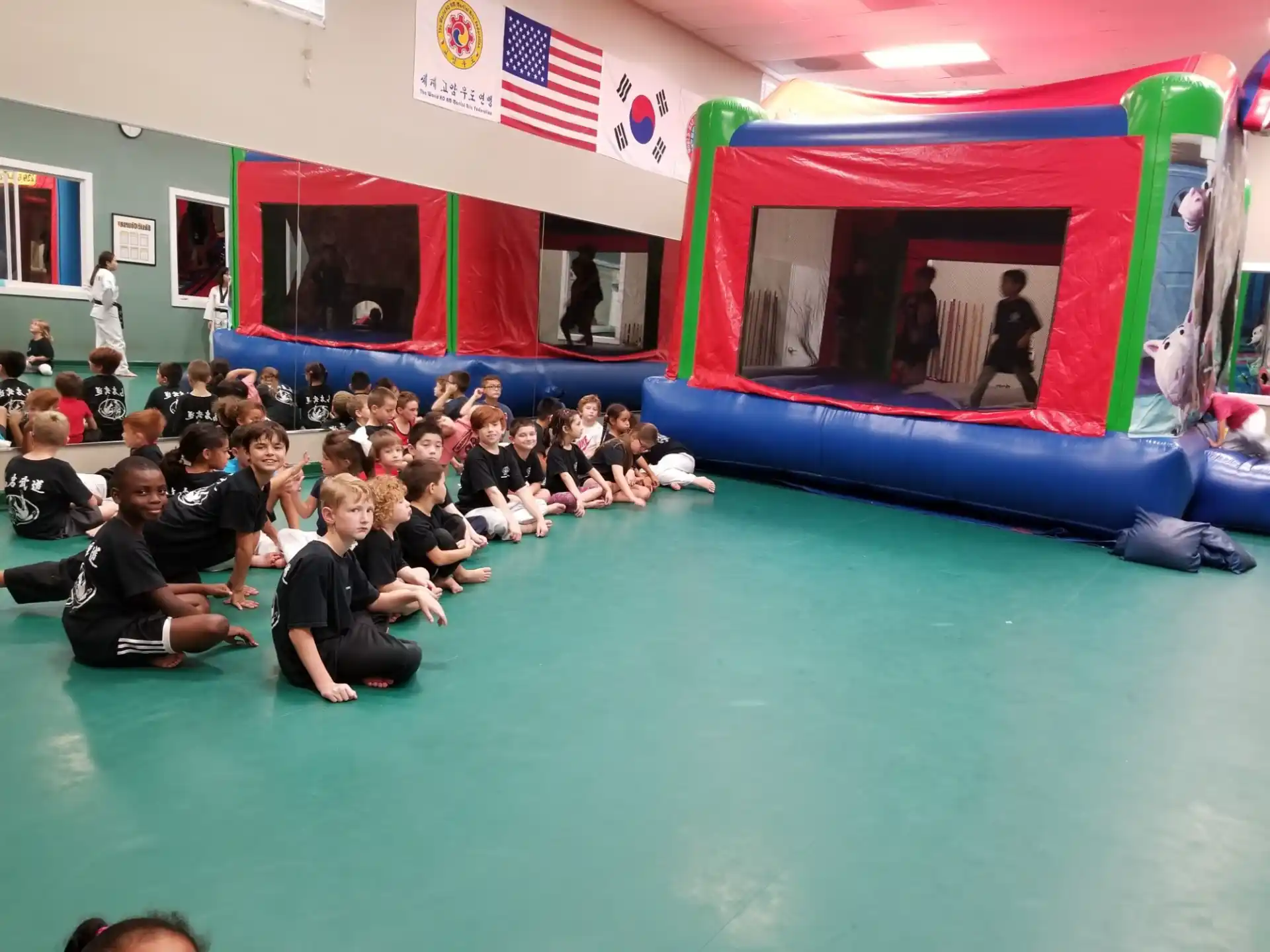 a group of people sitting in a room with a stage and a flag