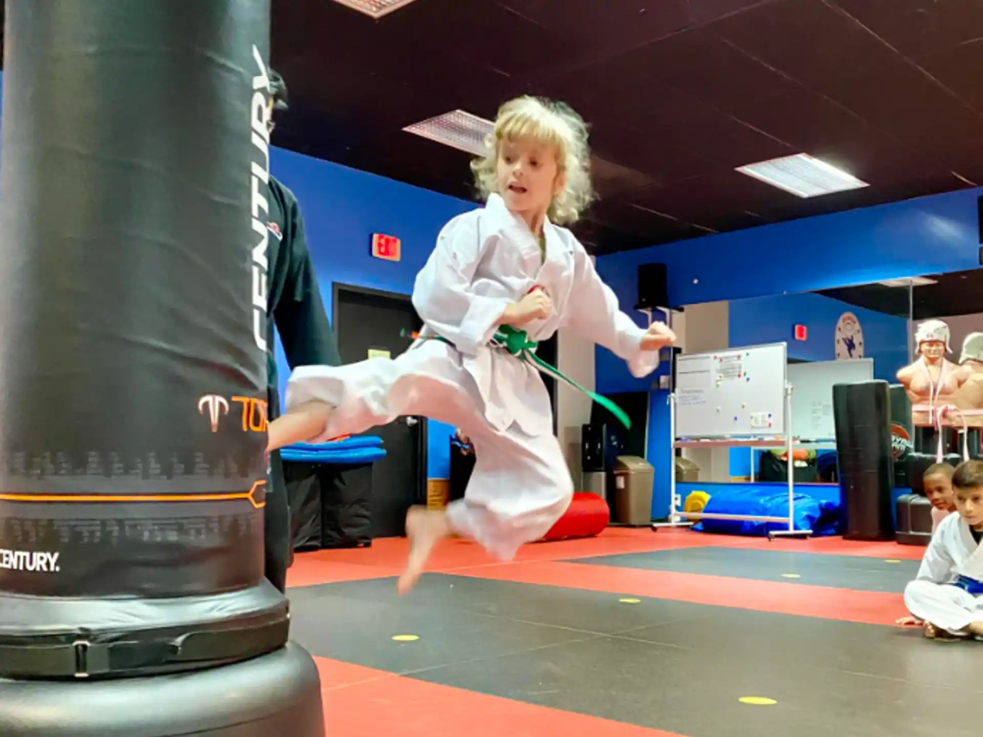 a girl in a white dress jumping on a trampoline