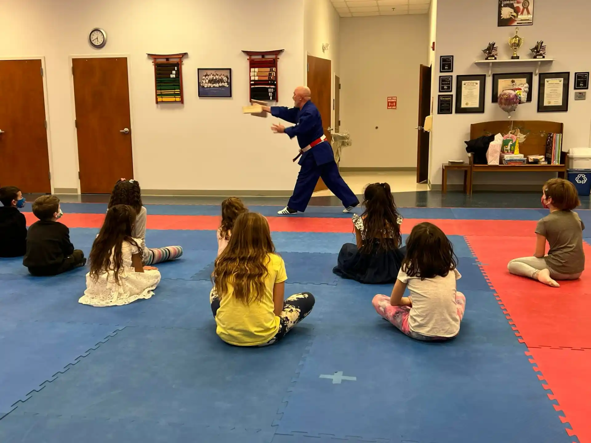 a person standing in front of a group of children sitting on the floor