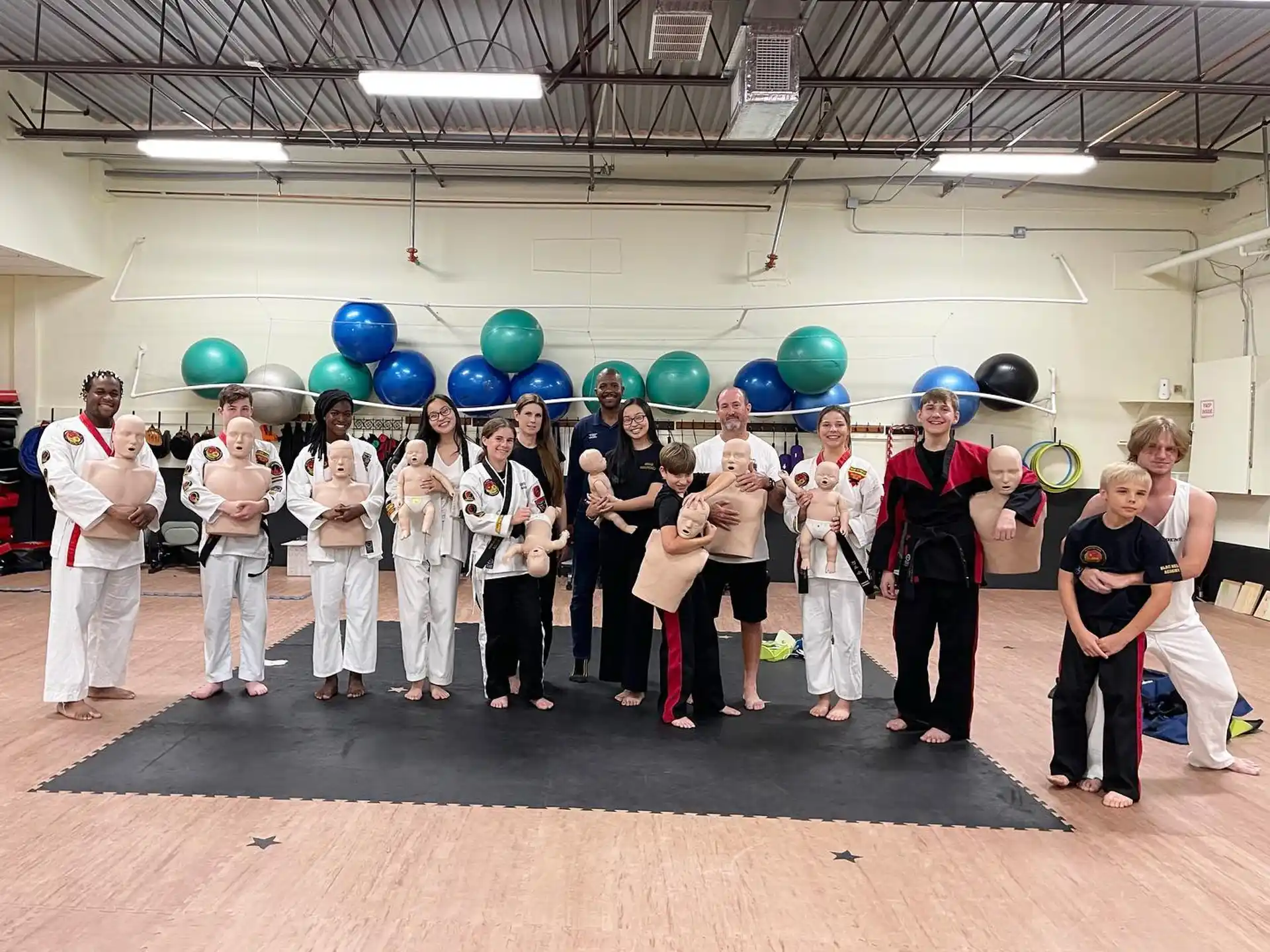 a group of people in white karate uniforms holding blue and green balloons