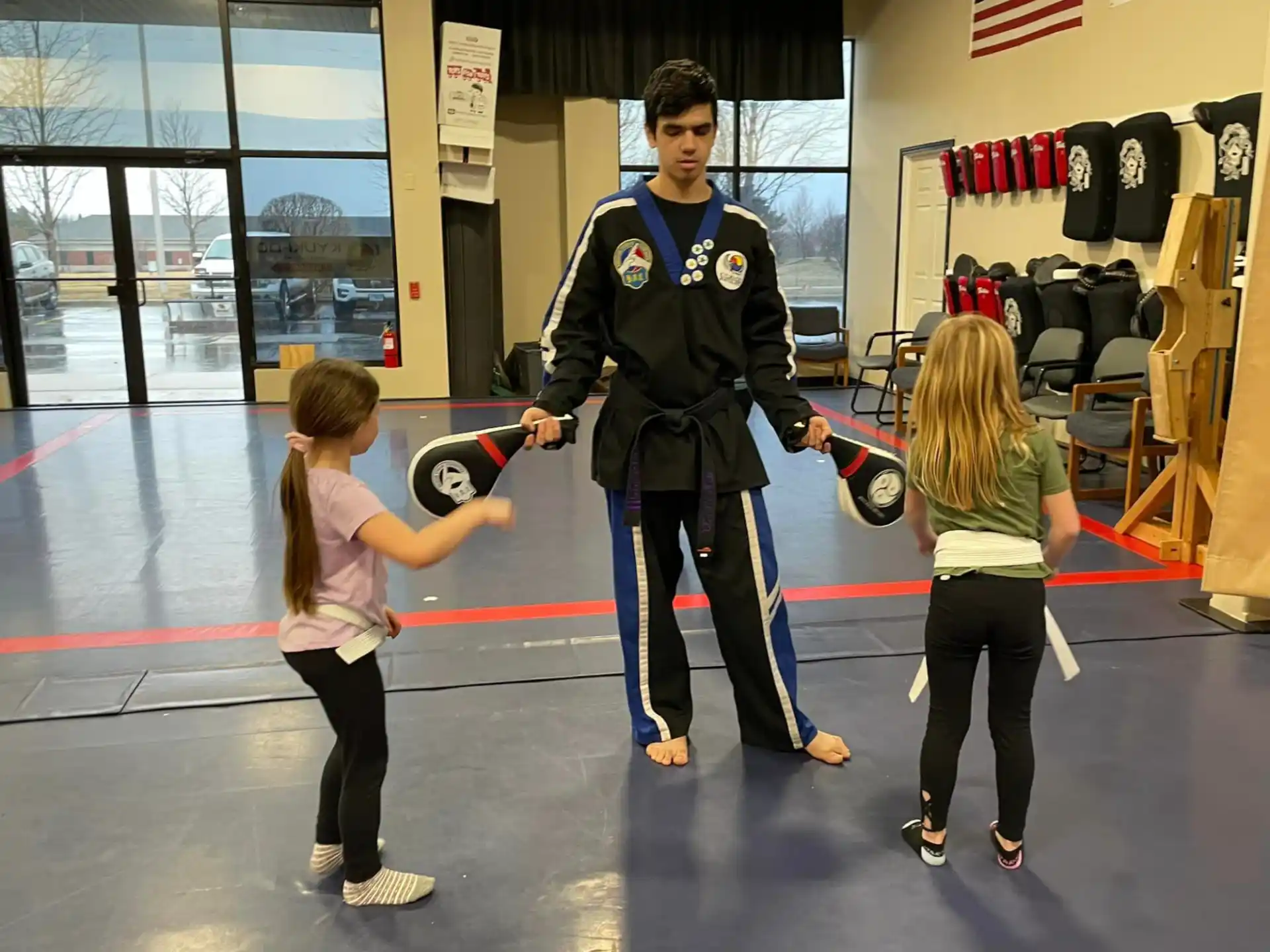 a person holding a rope with two girls standing on a gym floor
