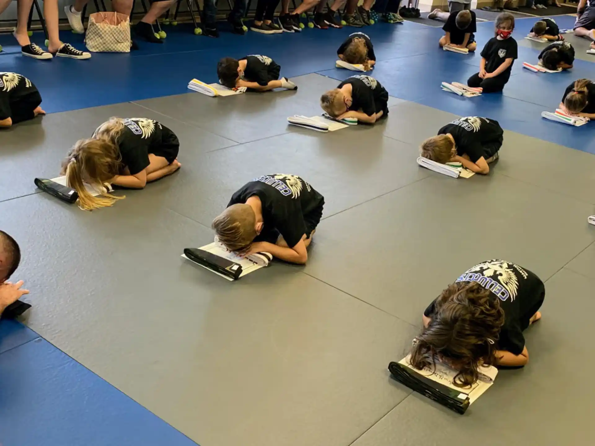 a group of people sitting on the floor writing on paper