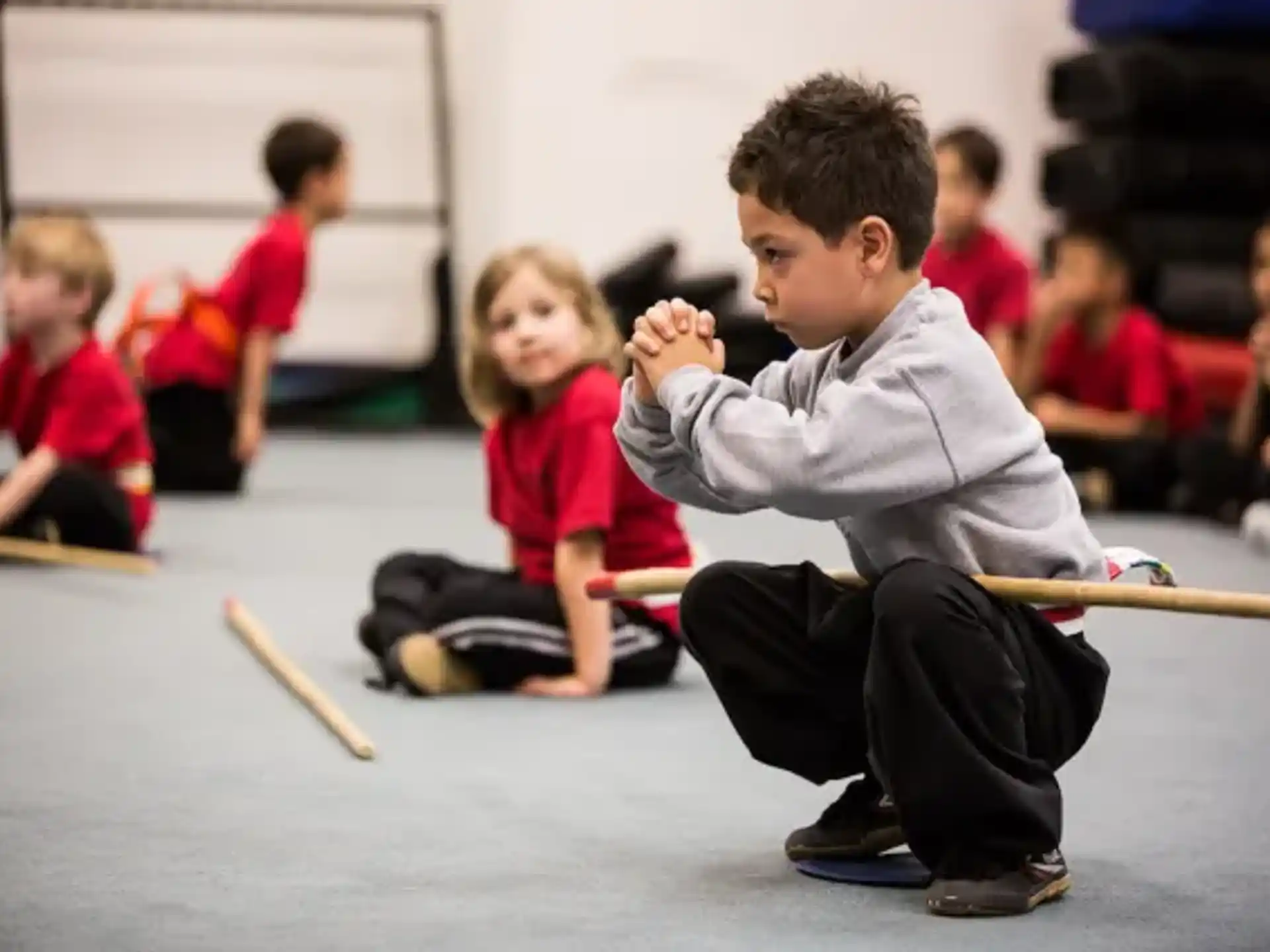 a group of children sitting on the floor playing with sticks