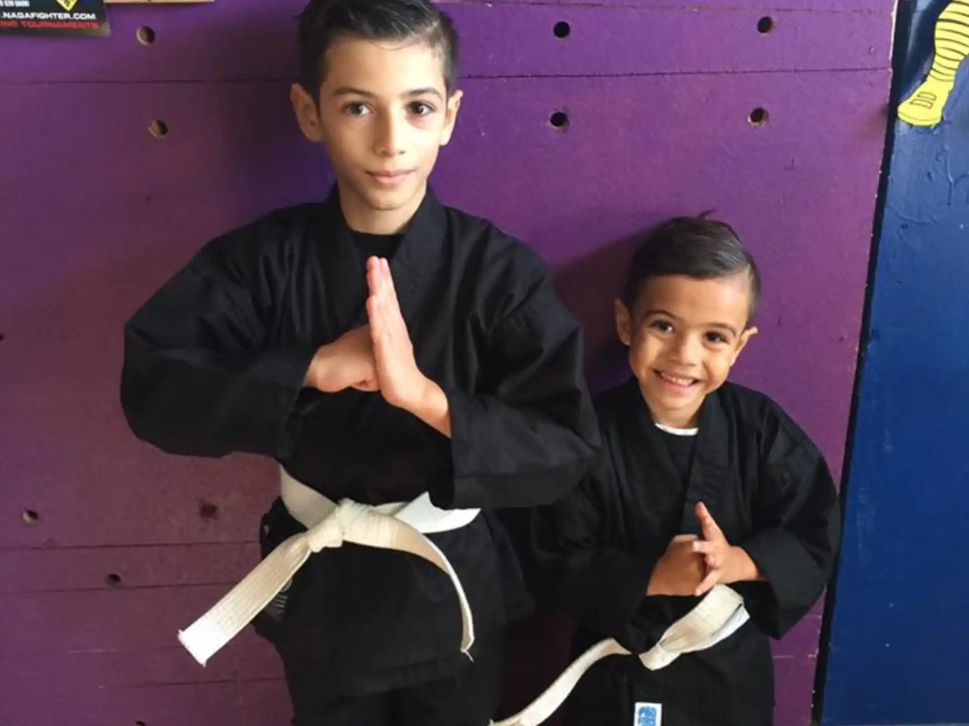 a couple of boys in black karate uniforms holding white paper