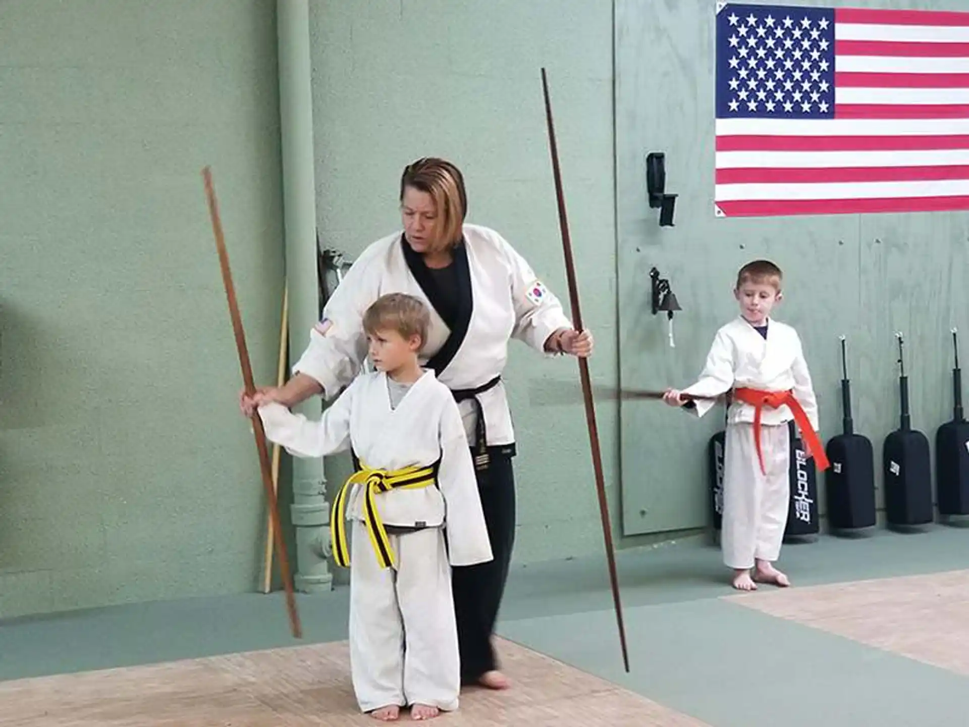 a person and two boys in karate uniforms holding swords