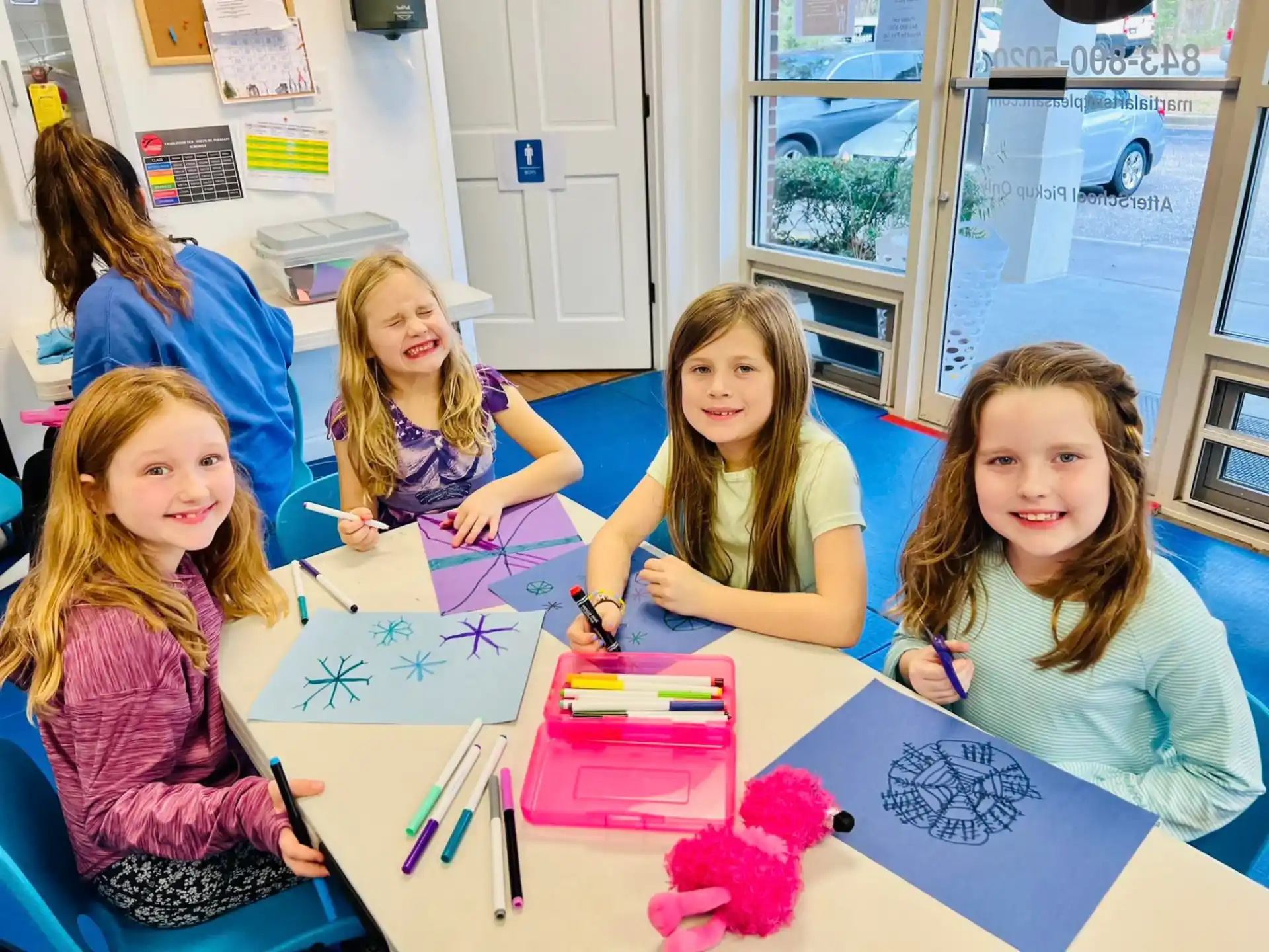 a group of girls sitting at a table with a drawing