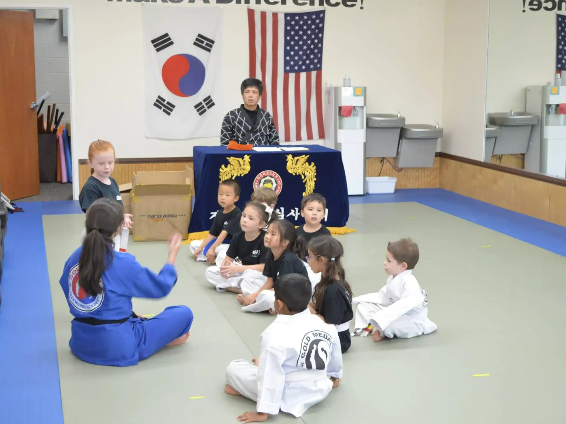 a group of children sitting on the floor in front of a person standing