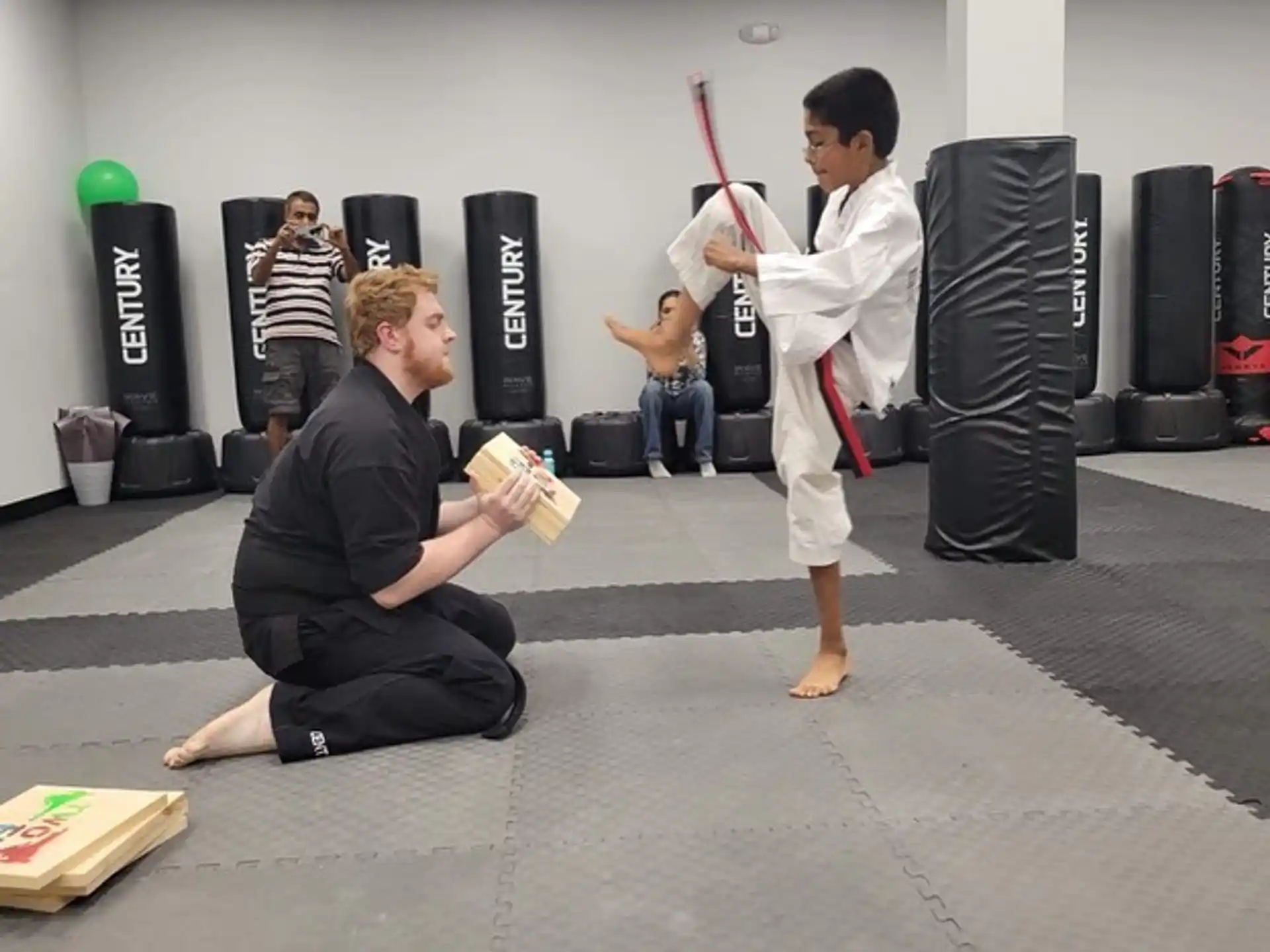 a man kneeling down next to a man in a karate uniform