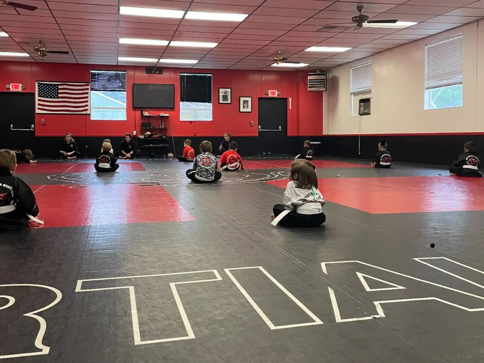 a group of people sitting on the floor in a gym