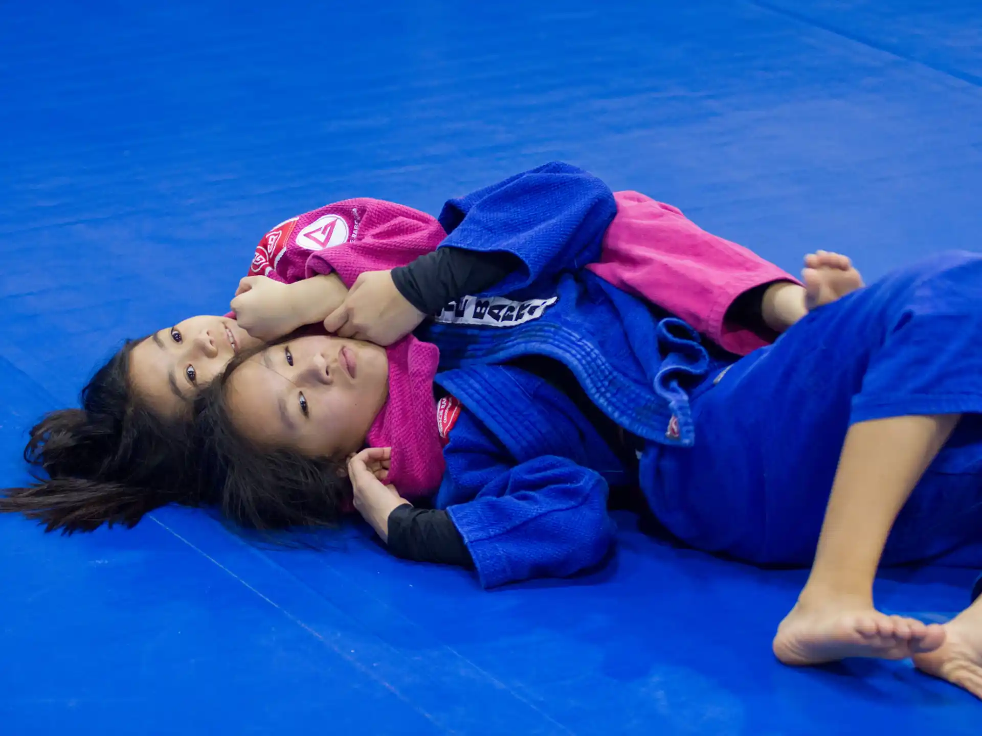 a person and a baby lying on a blue mat