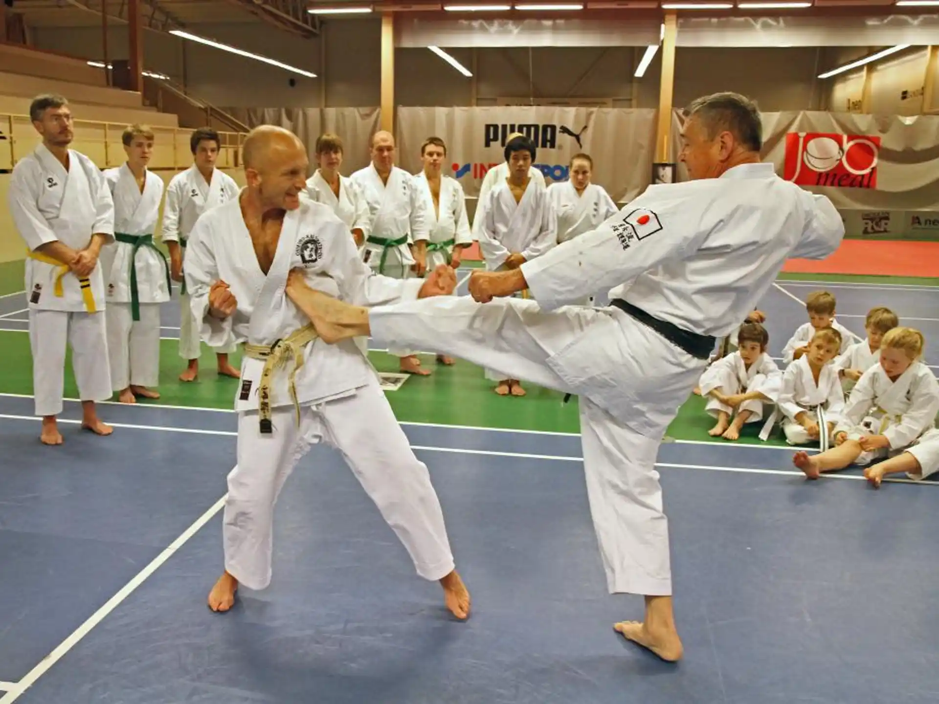 a man and a woman in karate uniforms with a crowd watching