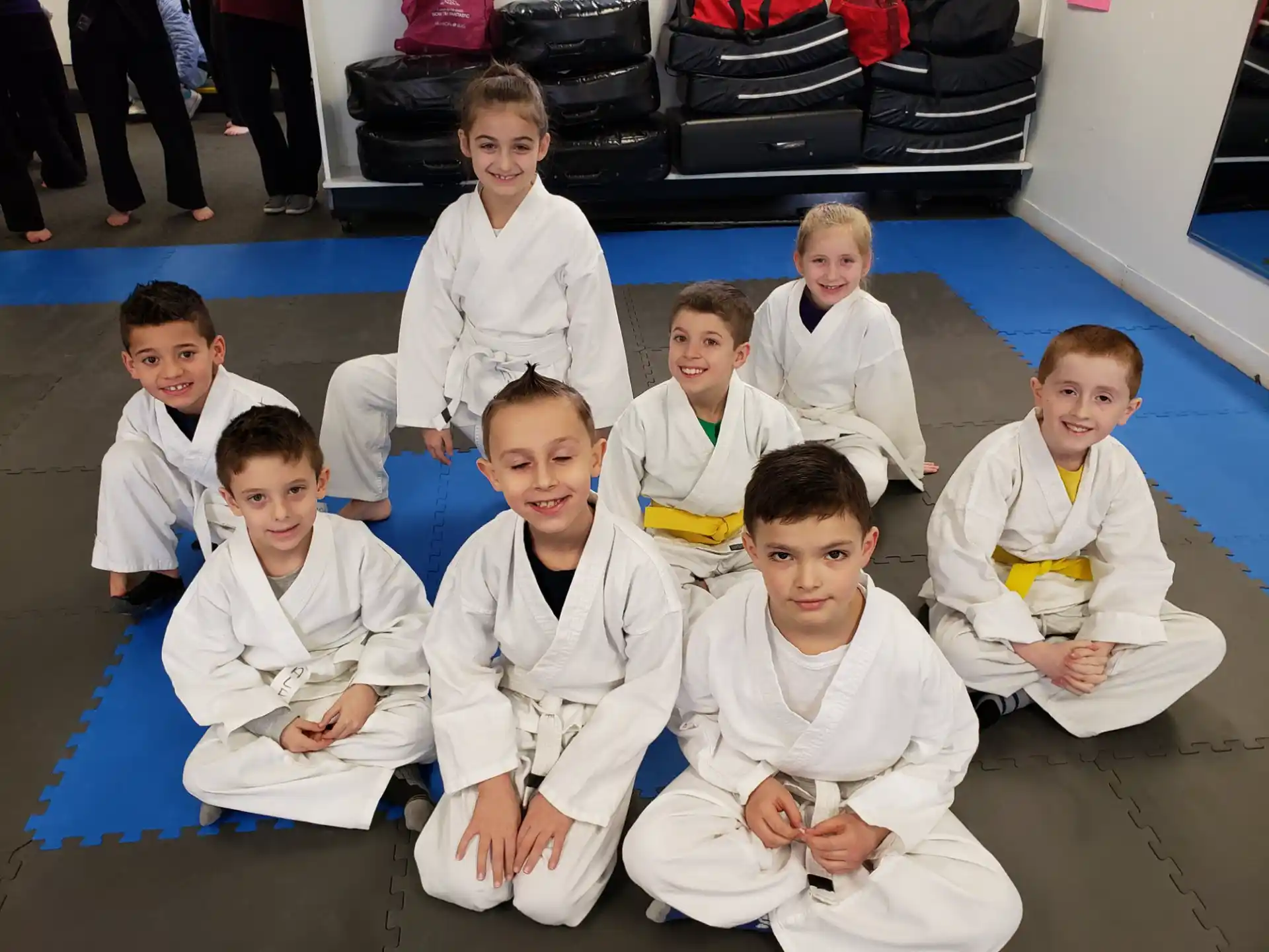 a group of boys in white karate uniforms sitting on the floor